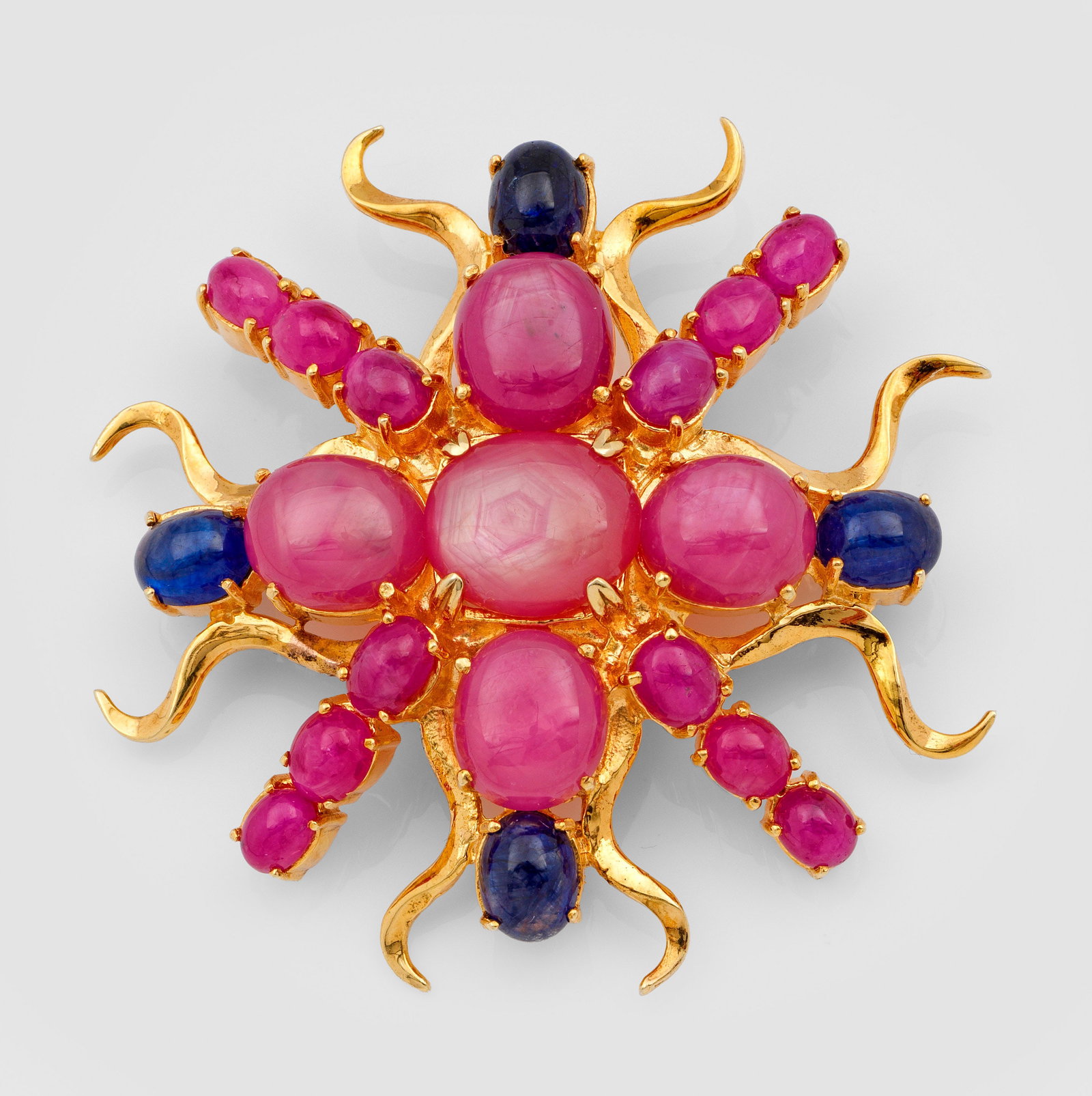 Glamouröse Saphir-Rubinbrosche: Silber, vergoldet. Schauseitig besetzt mit dunkelblauen Saphiren und framboisefarbenen Rubincabochons. Gew. ca. 32,63 g. Auch als Anhänger tragbar. Brooch/pendant set with sapphires and rubies, in si