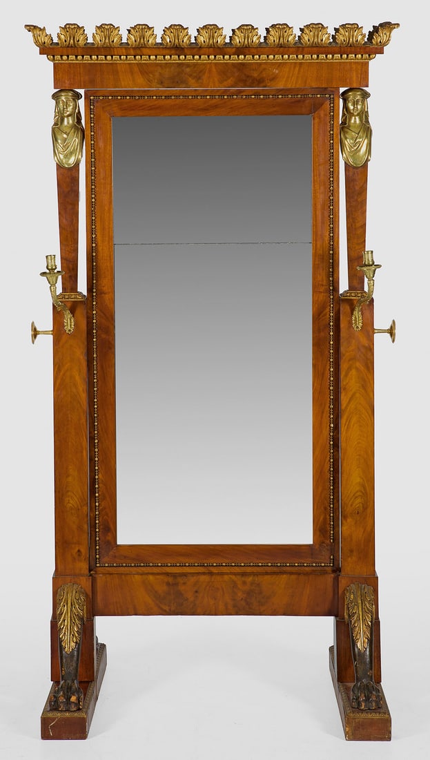 Große Empire-Psyche: Mahagoni, furniert sowie teilw. geschnitzt, gefasst und vergoldet sowie vergoldete Bronze. Über breiten Kufen, kräftig gekantete, gestuft angeordnete Streben mit weiblichen Karyatiden, flankiert von