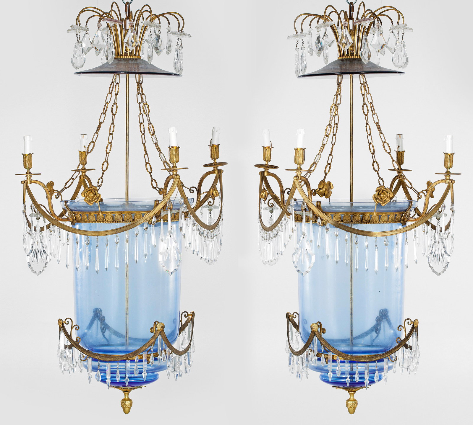 Paar große repräsentative Empire-Deckenampeln: 4-flg.; Messing, hellblaues Glas und farbloses Kristallglas. Balusterförmiger Korpus, umgeben von durchbrochen gearbeitetem Palmettenfries sowie festonartigen, gebogten Streben mit reichem Behang aus