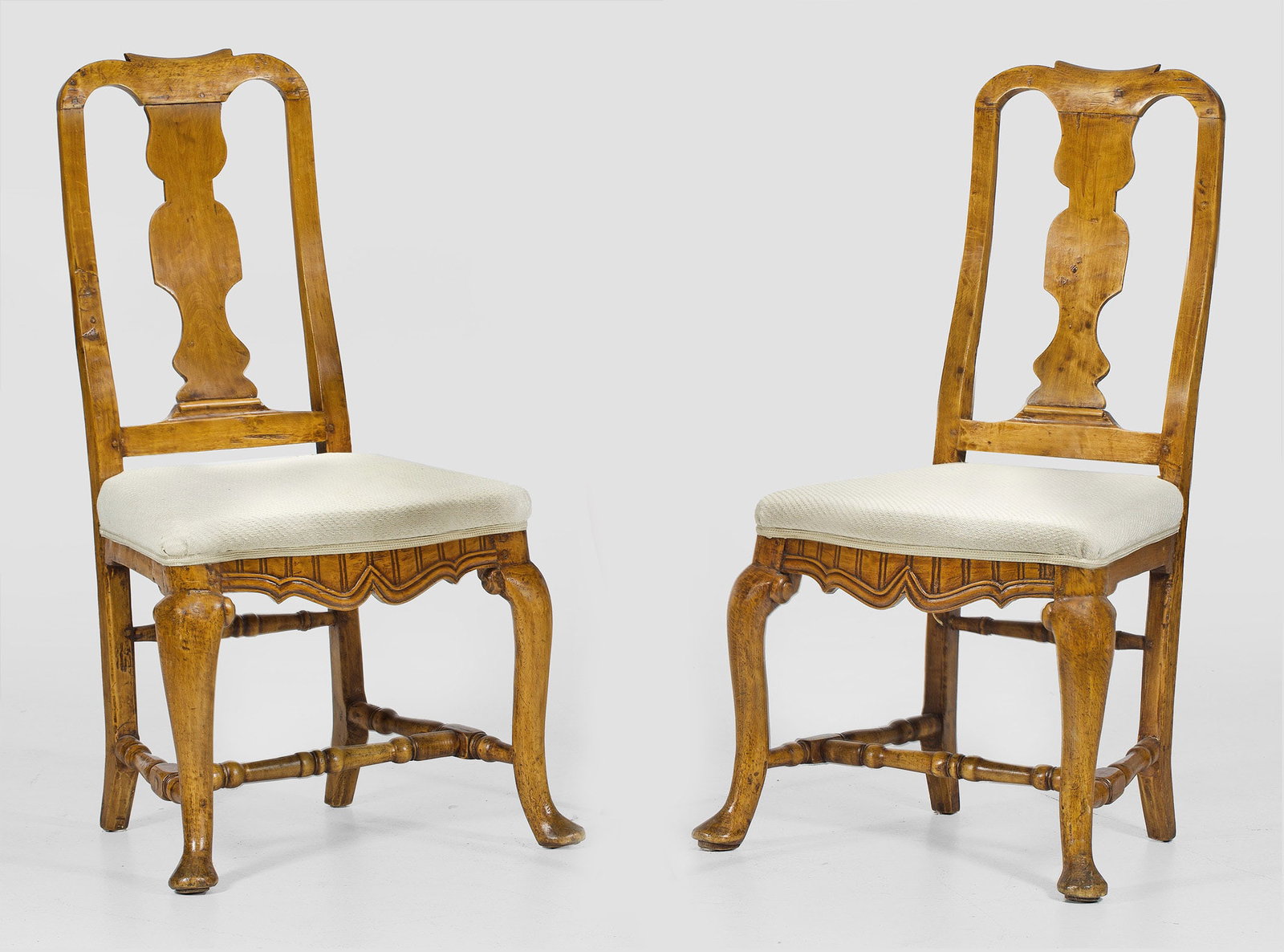Paar Barock-Stühle: Nussbaum. Trapezförmige, leicht bombierte Zarge auf geschwungenen Beinen, unterhalb durch Balusterstäbe verbunden. Leicht zurückschwingende Rückenlehne mit balusterförmigem Mittelsteg. Sitzfläch