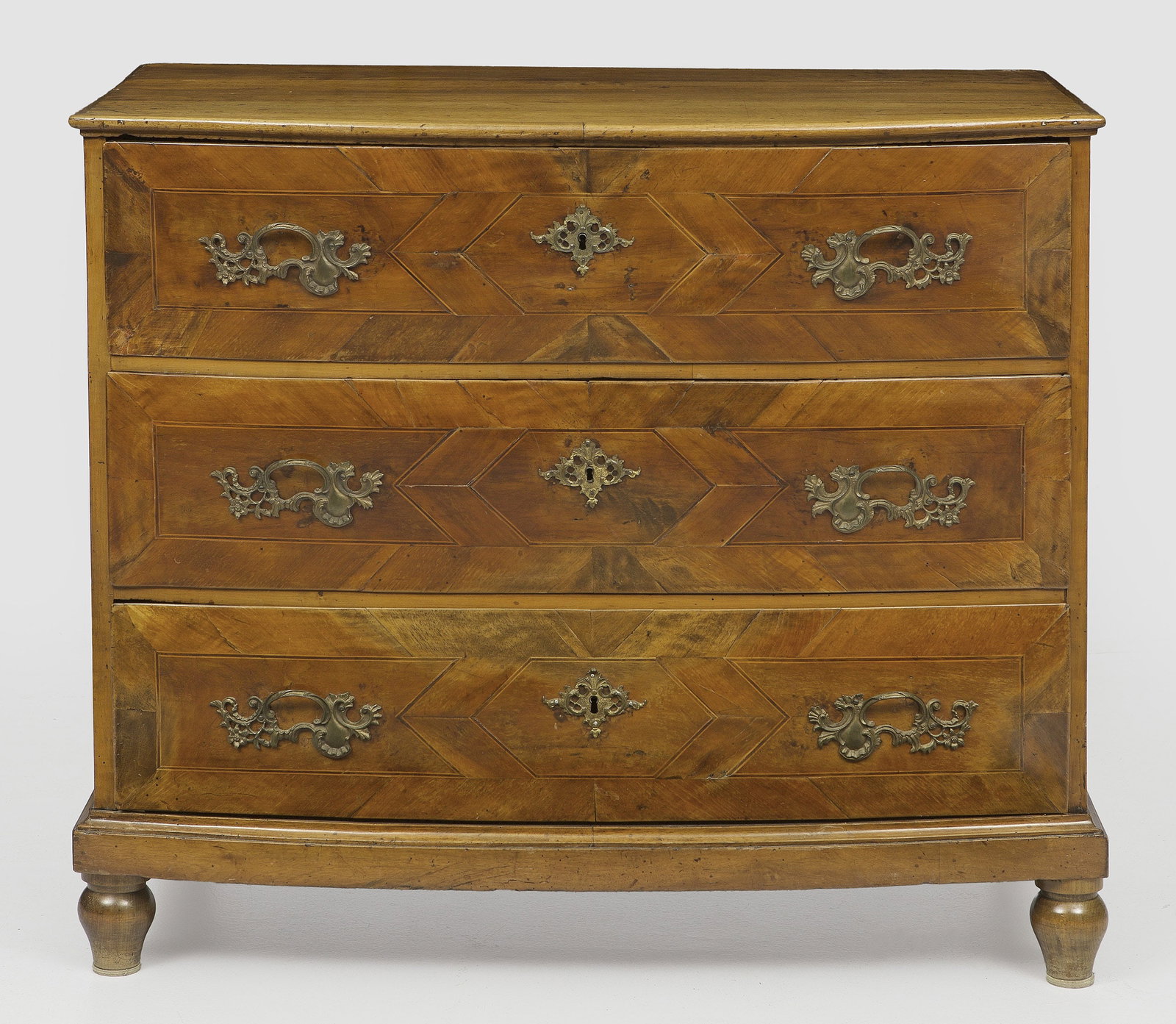 Große Barock-Kommode: Nussbaum, furniert. Gerader, rechteckig angelegter Korpus auf schmaler Zarge und Balusterfüßen. In der gegliederten Front drei breite ausgebogte Schubladen. Gering überstehende Deckplatte. Flächen