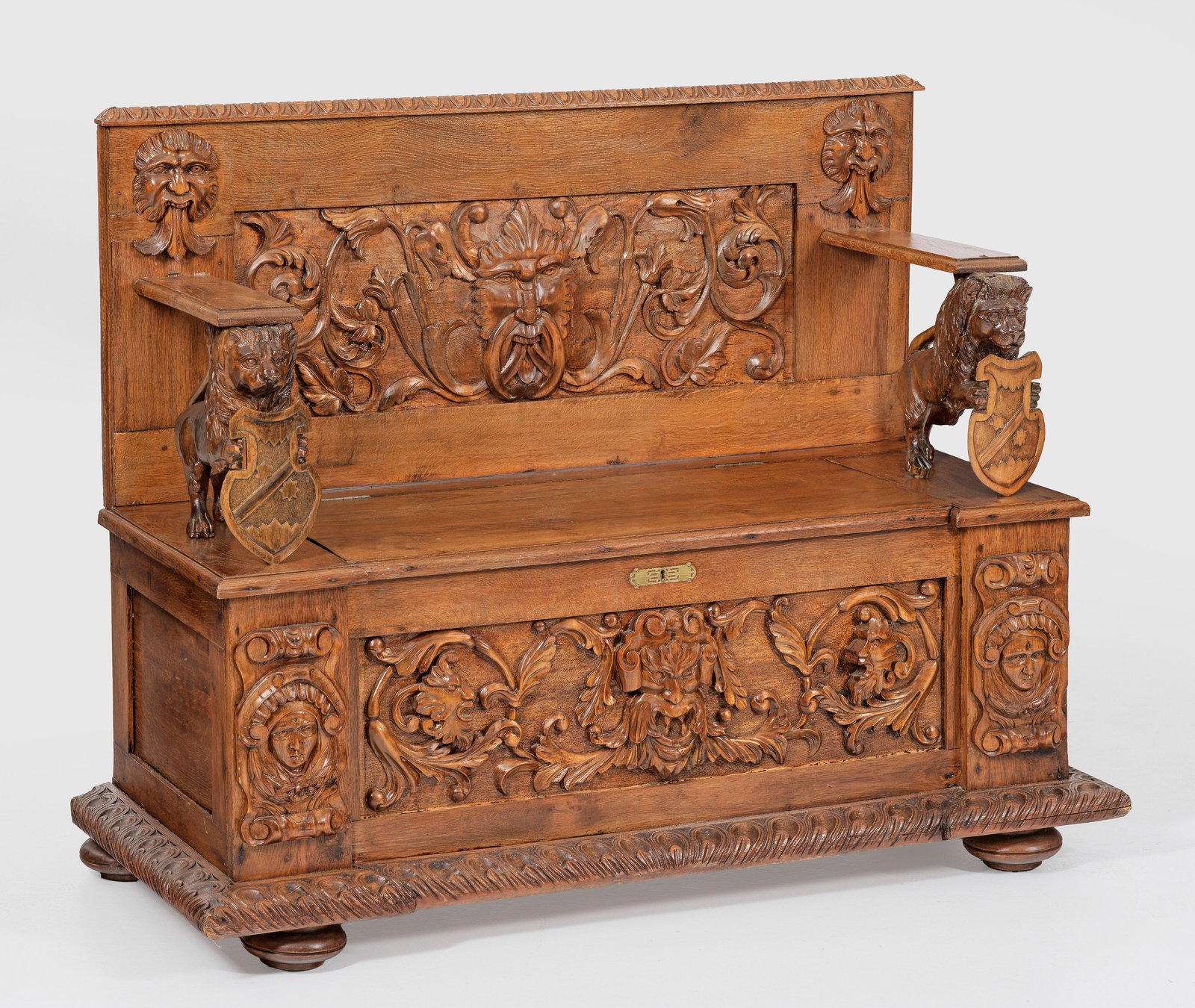 Historismus-Truhenbank: Eichenholz, reliefplastisch geschnitzt. Gerader, querrechteckig angelegter Korpus auf breitem Zargensockel und gedrückten Füßen. Aufklappbare Deckplatte. Korrespondierende Rückwand, flankiert von