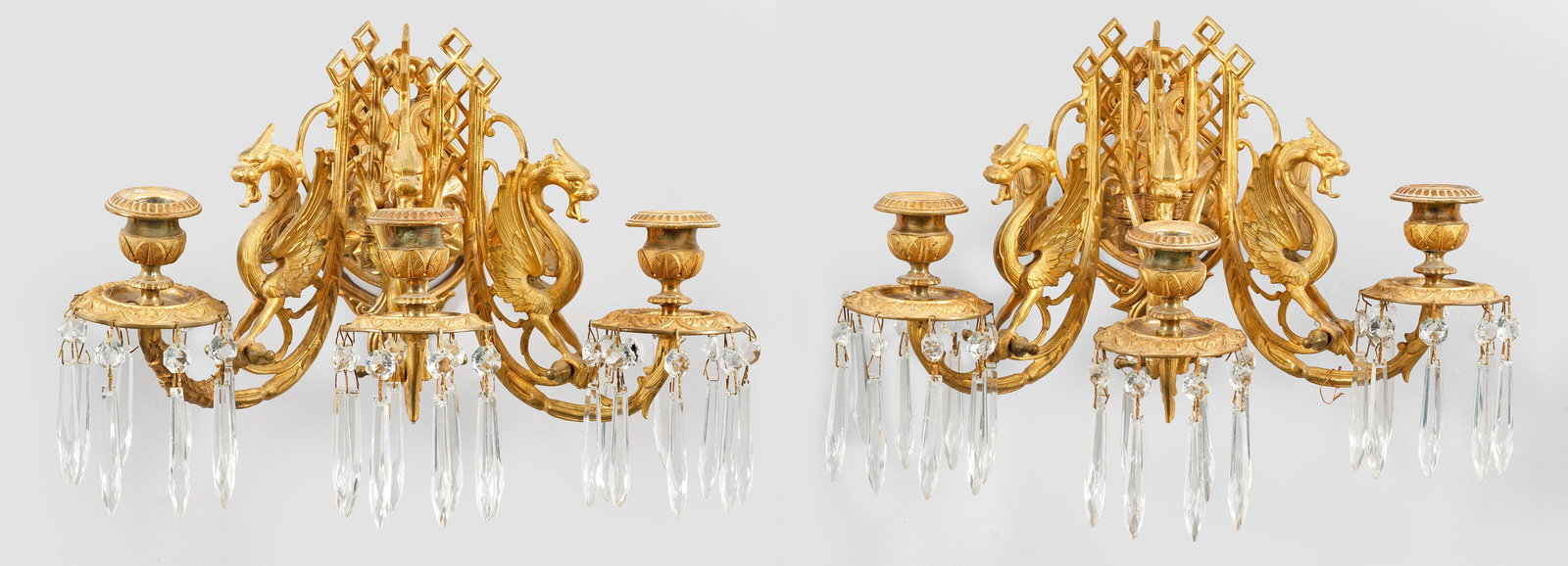 Paar Napoleon III-Wandleuchter: 3-flg.; Messing und farbloses Glas. Balusterförmiges Wandschild. Davon ausgehend durchbrochen gearbeitete Leuchterarme mit plastischen Drachen und vasenförmigen Tüllen. Behang aus facettierten Pris