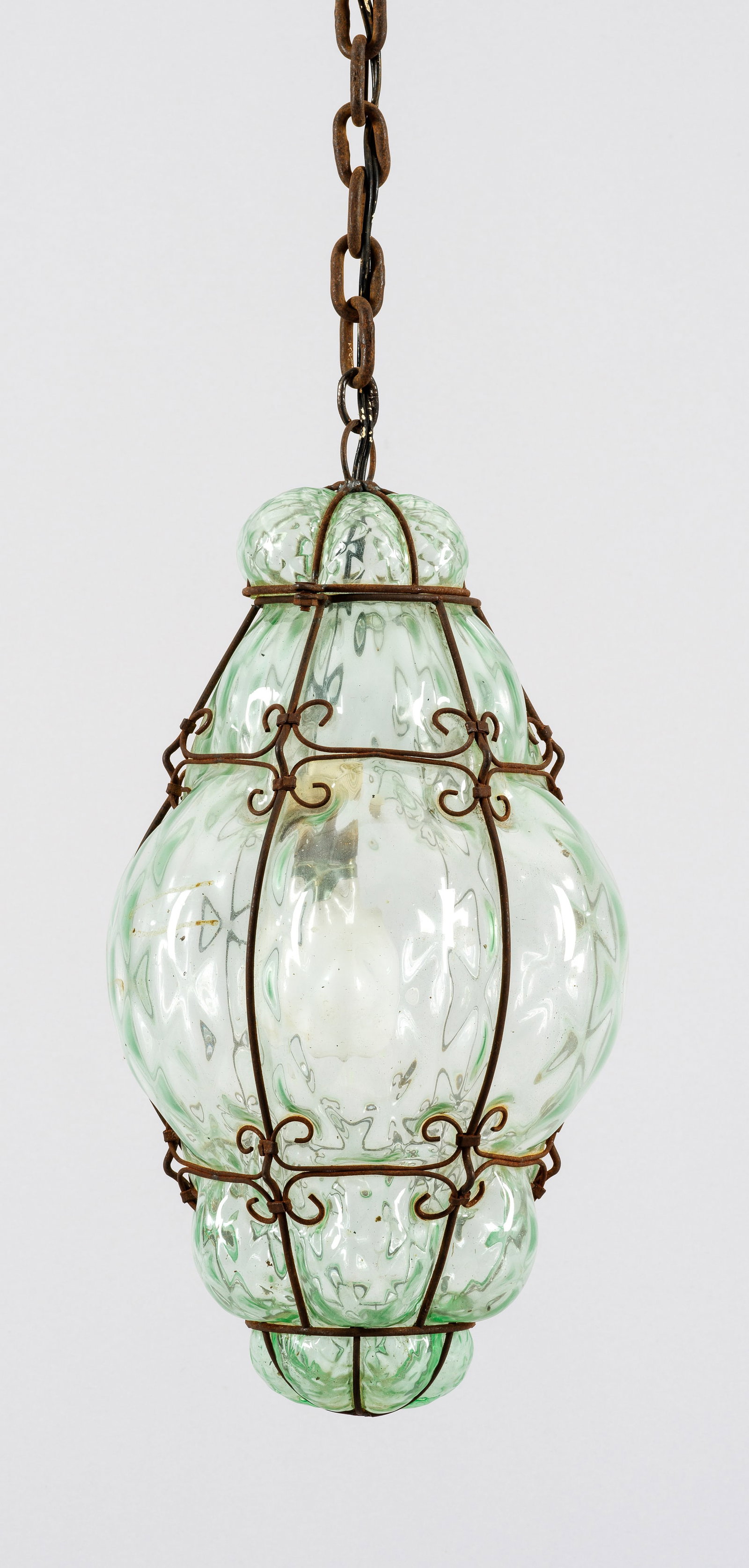 Deckenlampe: 1-flg.; Grünliches Glas und Metall mit Rostpatina. Balusterförmiger, stark ausgewölbter Korpus umspannt von schmalen Streben. Innen eine Lampenfassung. Elektrifiziert. H. 42 cm. A French glass and