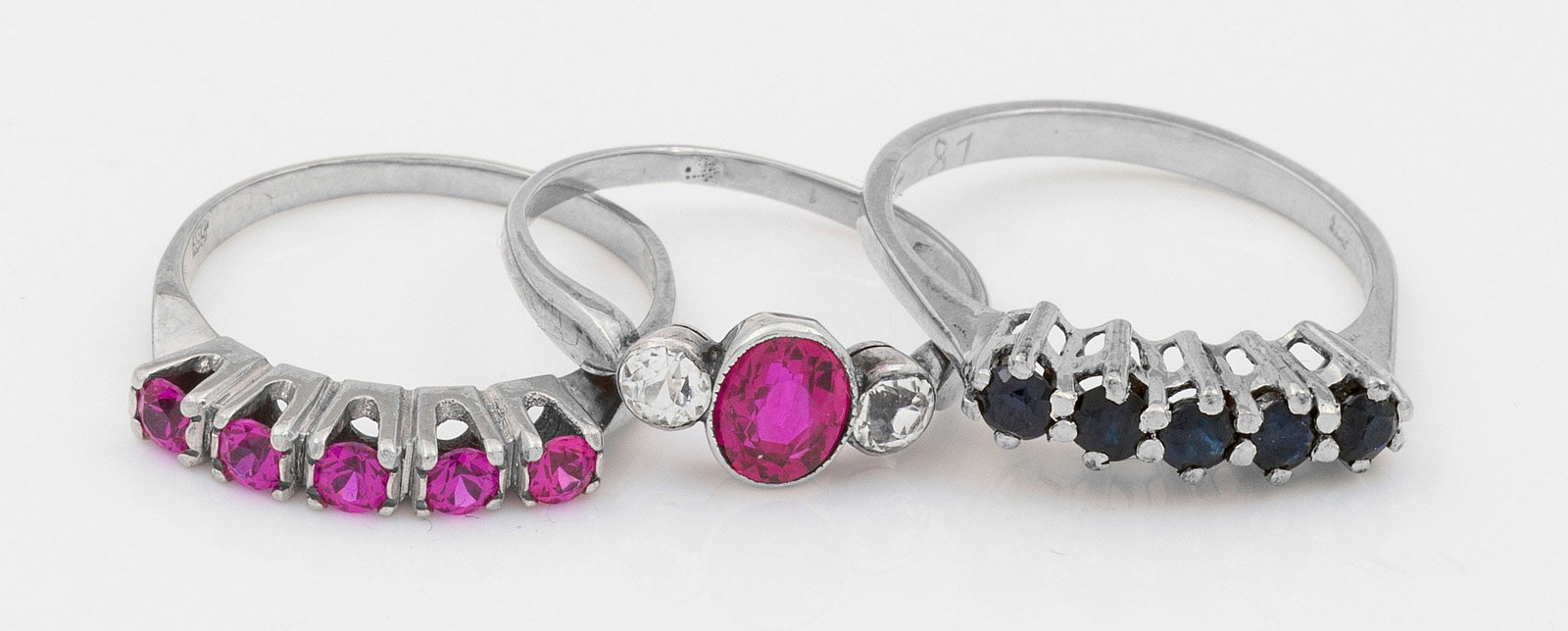 Drei Rubin-Saphirringe: Gelb- und Weißgold, 14 ct.; Linear besetzt mit Saphiren und Rubinen sowie einem pinkfarbenen Farbstein mit Strasssteinen. Ges.-Gew. ca. 6,70 g. Three rings set with pink stone, rhinestones, sapphires