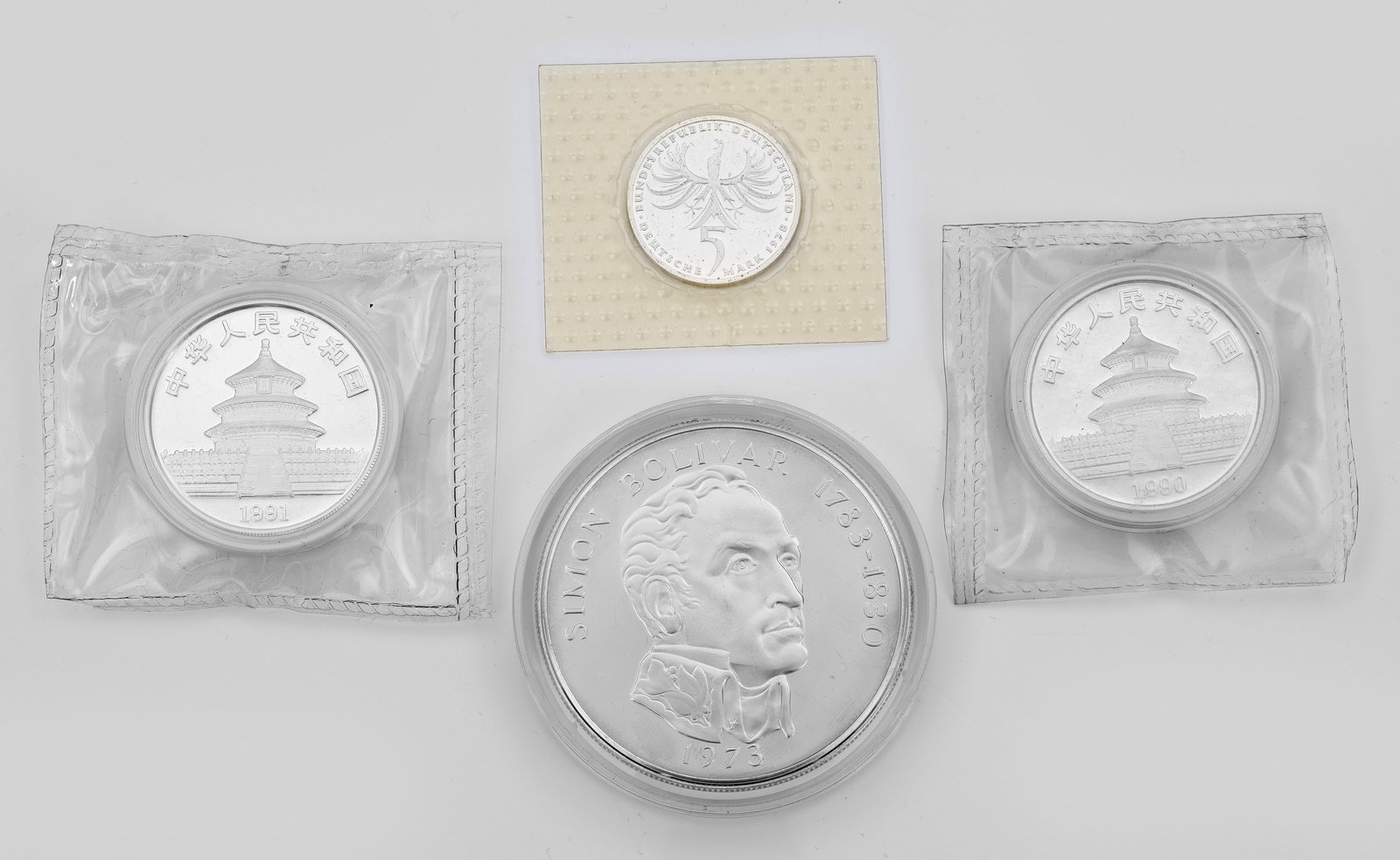 Vier Silbermünzen: 20 Balboas Sterlingsilber-Münze der Republik Panama mit Simon Bolivar (1783-1830), 1974. Zwei 10 Yuan-Feinsilbermünzen mit Pandamotiven aus den Jahren 1990 und 1991, 5 Deutsche Mark-Münze mit Balth