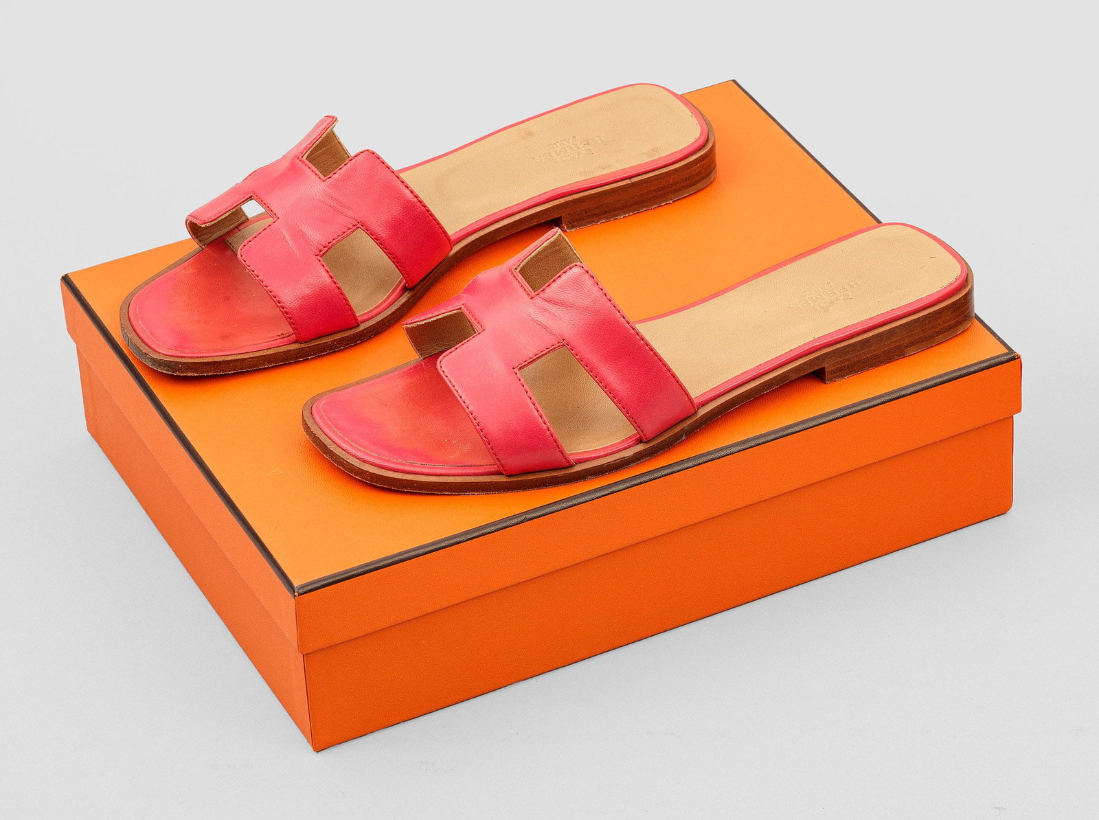 Paar Damen-Sandalen "Oran" von HERMÈS: Papayafarbenes Leder. Flache Sandale mit breitem Riegel aus stilisiertem H-Logo. Gr. 38,5. Getragen. Original Box und Staubbeutel. A pair of pre-owned papaye coloured leather sandals by HERMÈS. Box a