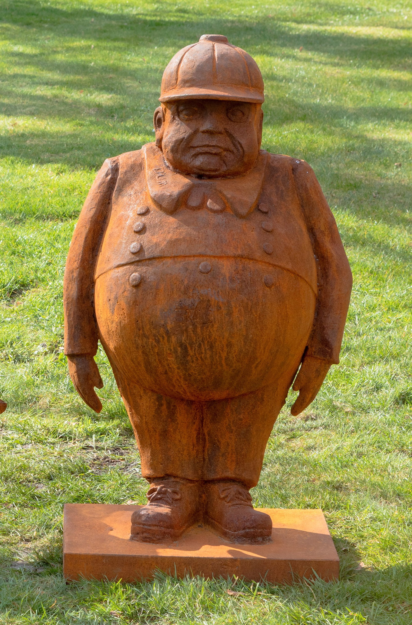 Zeitgenössischer Bildhauer: (Tätig im 20./21. Jh.) Gartenfigur aus "Alice hinter den Spiegeln" Gusseisen, rostbraun patiniert. Auf rechteckiger Plinthe stehender, beleibter Herr mit Schirmmütze, einen der ikonischen Zwillingsb