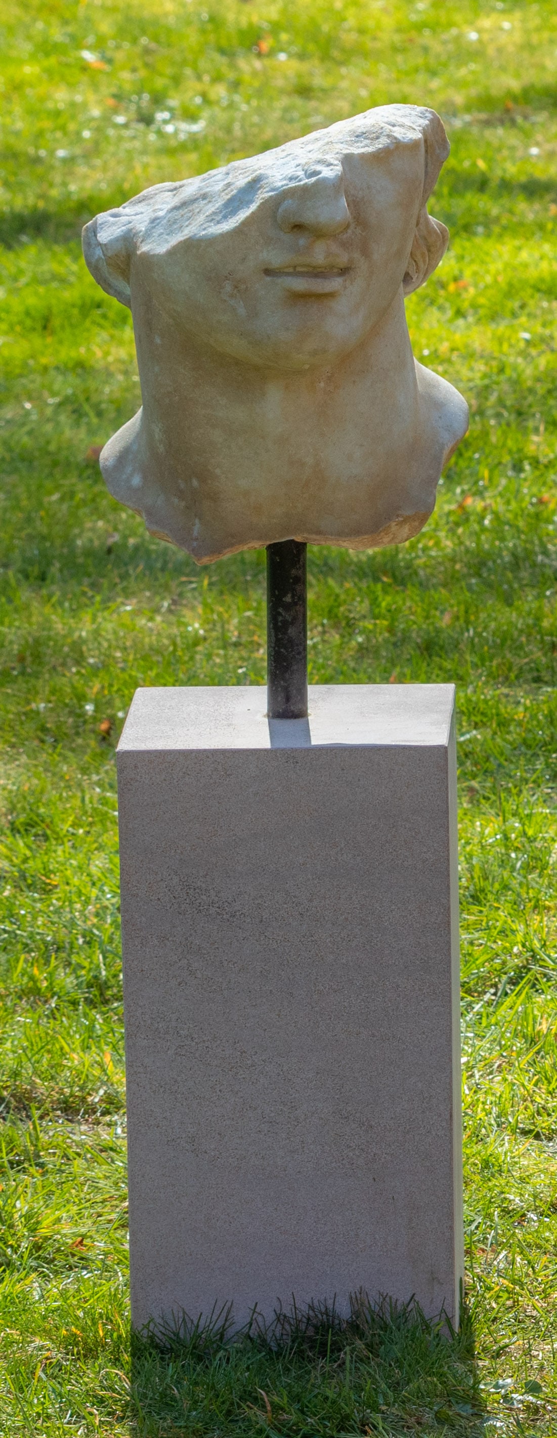 Italienischer Bildhauer: (Tätig im 20. Jh.) Büstenfragment des Apollo Heller Marmor auf hochrechteckigem Travertinsockel. Fragmentarisch erhaltene Büste des Apollo nach einem hellinistischen Vorbild, ausgestellt im Metropo