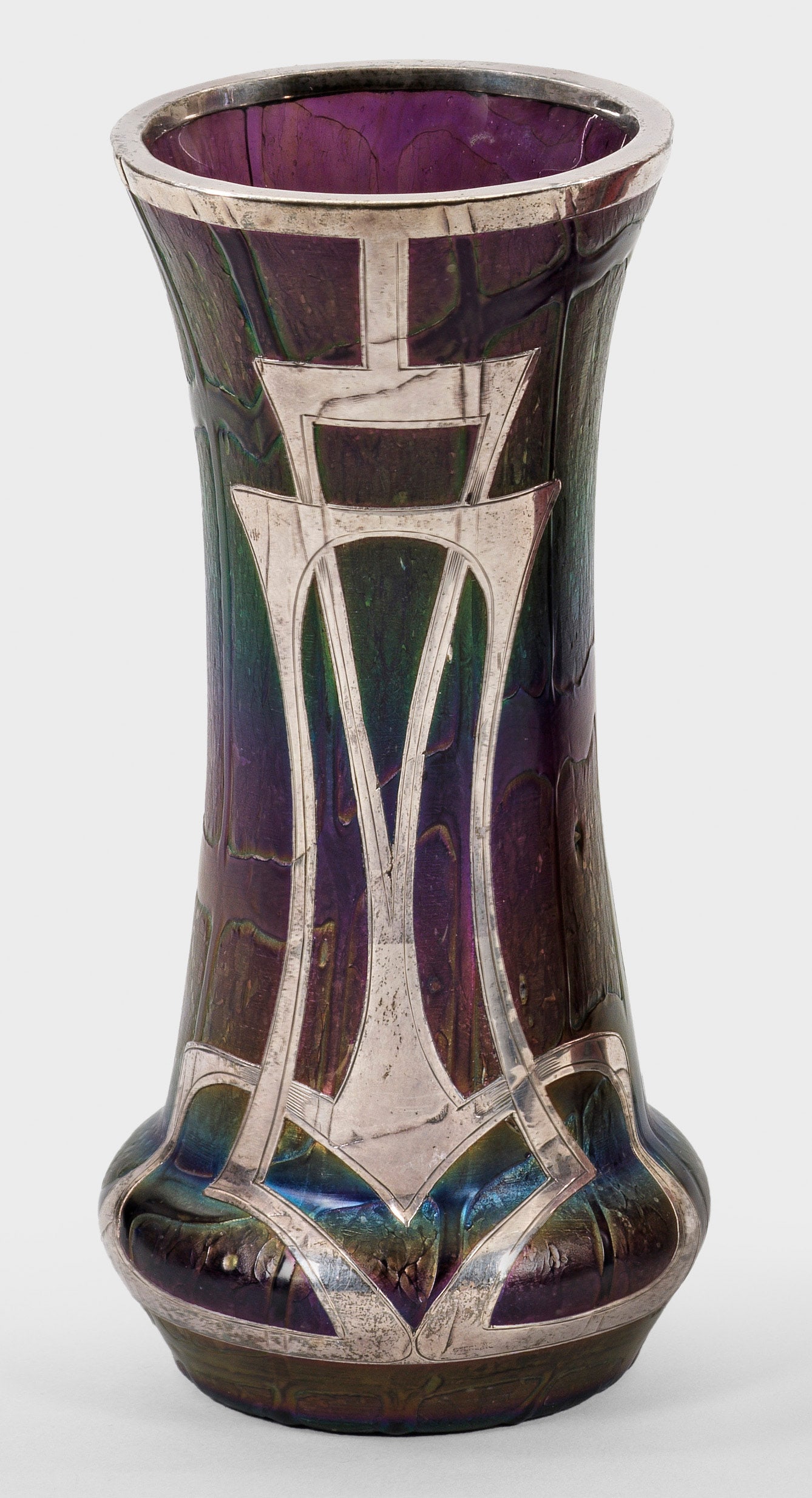 Böhmische Jugendstil-Ziervase mit Feinsilber-Auflage: Schlanke, unterhalb gebauchte Form. Violettes Glas mit unregelmäßig aufgesonnenen Fäden, reduziert und irisiert. Schauseitig galvanische Feinsilber-Auflage mit Linienornamentik. H. 14,3 cm. A Bohem
