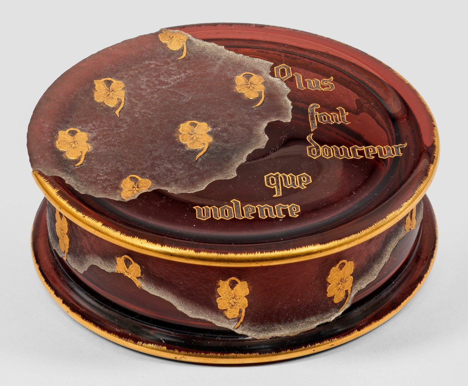 Seltene Zierdose von Daum Frères: Flache, zylindrische Form mit vorkragendem Fuß- und Deckelrand. Bordeauxrotes Glas. Dekor geätzt und in Goldmalerei aus unregelmäßig geschwungenen Flächen mit einzelnen Veilchenblüten als symbol