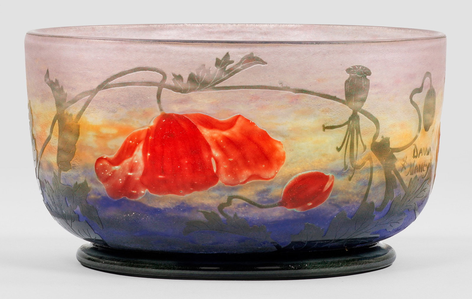 Seltene Jugendstil-Zierschale mit Mohn-Dekor von Daum Frères: Runde, flach-zylindrische, unterhalb gerundete Form auf niedrigem Profilfuß. Überfangglas, farblos und mit flockigen Pulvereinschmelzungen in Weiß, Ockergelb und Dunkelblau, die Außenschicht mit P