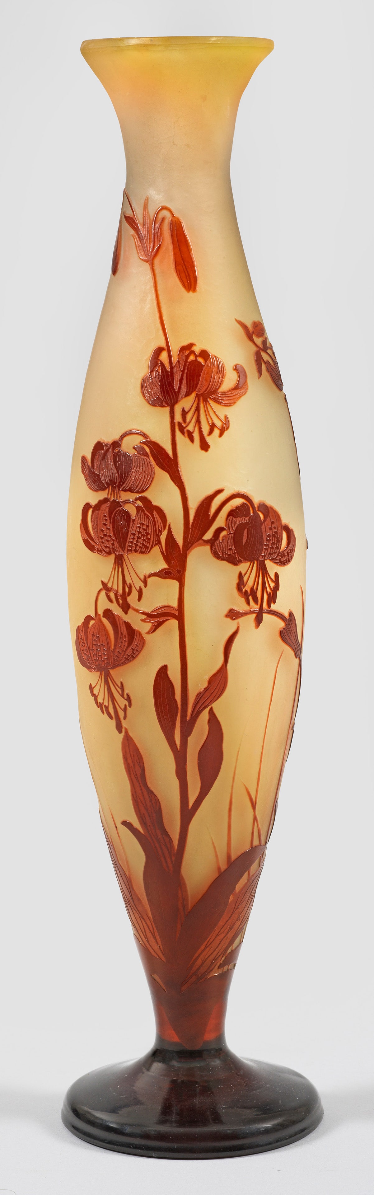 Große Emile Gallé-Ziervase mit Türkenbund-Lilien-Dekor: Schlanke, hohe Balusterform aus weit ausgestelltem Fuß. Überfangglas, farblos, opalisierend, bernsteingelb und bordeauxrot (bzw. violett). Geätzter und polierter Dekor aus blühenden Türkenbund-Li