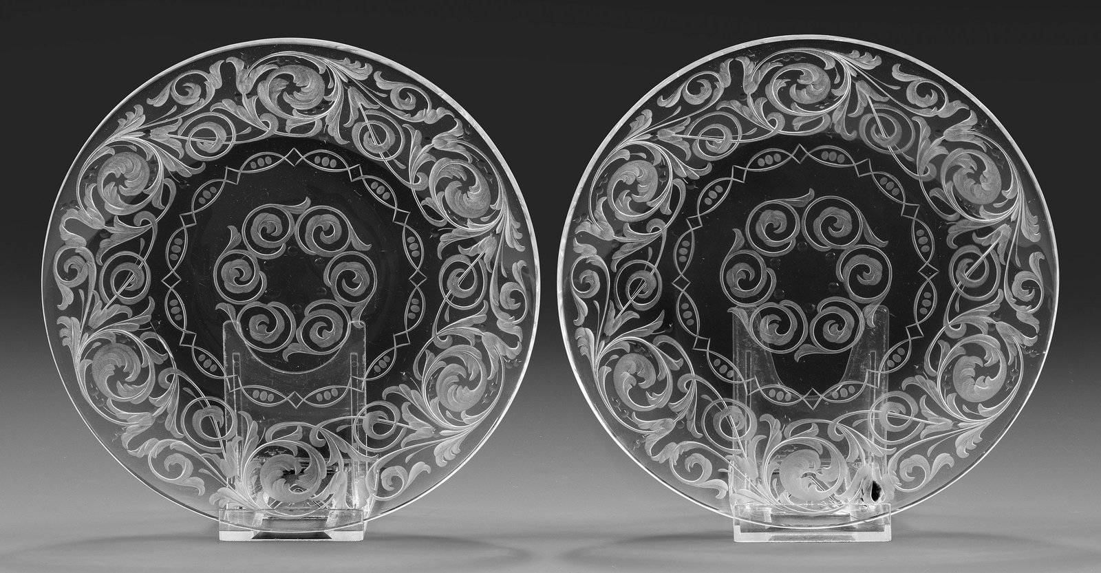 Paar Dessertteller mit opulentem Dekor: Farbloses Kristallglas. Flache Form. Reicher Dekor aus Akanthusranken und ornamentaler Bordüre, geschliffen und geschnitten. D. 19 cm. A pair of French cut and engraved crystal glass dessert plates, 