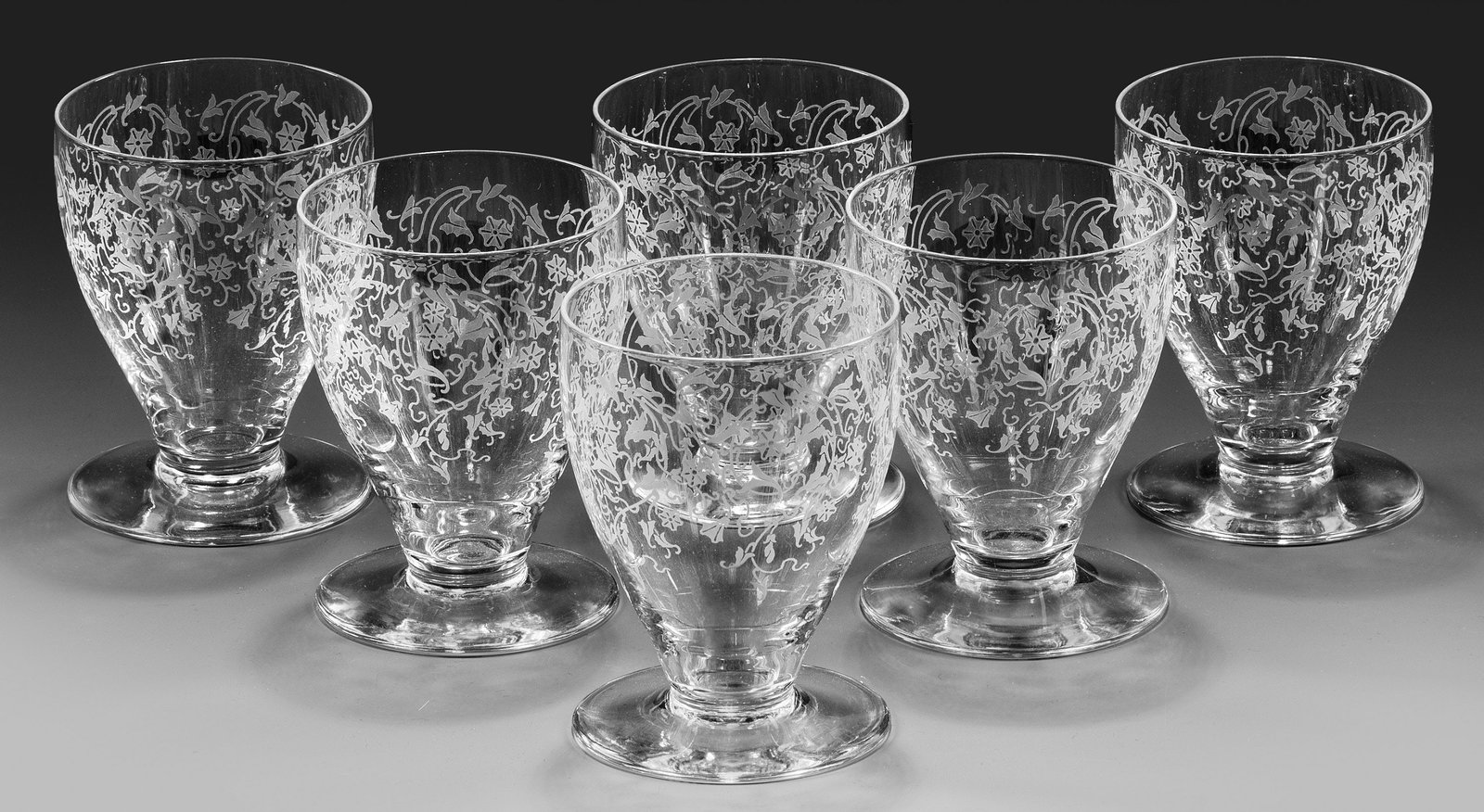 Sechs Wassergläser: Farbloses Kristallglas. Becherform mit ovoider Kuppa auf weit ausgestelltem Scheibenfuß. Geätzter Blüten- und Blattrankendekor. H. 10 cm. Six French crystal water glasses with acid-etched decor, pr