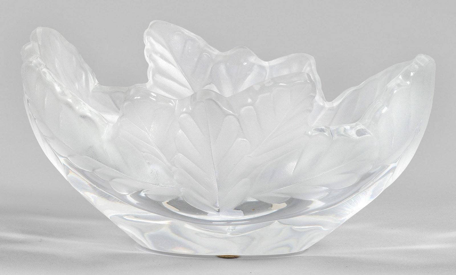 Lalique-Schale "Compiègne": Ovale Form mit stilisiertem Eichenblattrelief. Farbloses Kristallglas, partiell satiniert und geschliffen. Entw. Marc Lalique, 1966. Sign. "Lalique France ®" (diamantgeritzt). H. 9,5 cm; B. 19,5 cm. 