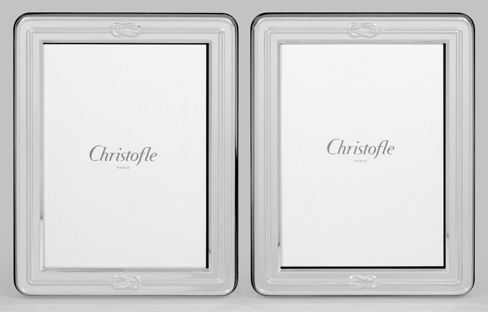 Paar Bilderrahmen von Christofle: Plated. Rechteckig mit gerundeten Ecken, Profillinien und Knotendekor. Rücks. aufstellbar. Mit Originalverpackung. Gem. Herstellerzeichen. 22,5 cm x 17,5 cm. Bildausschnitt 17,5 cm x 13 cm. A pair of