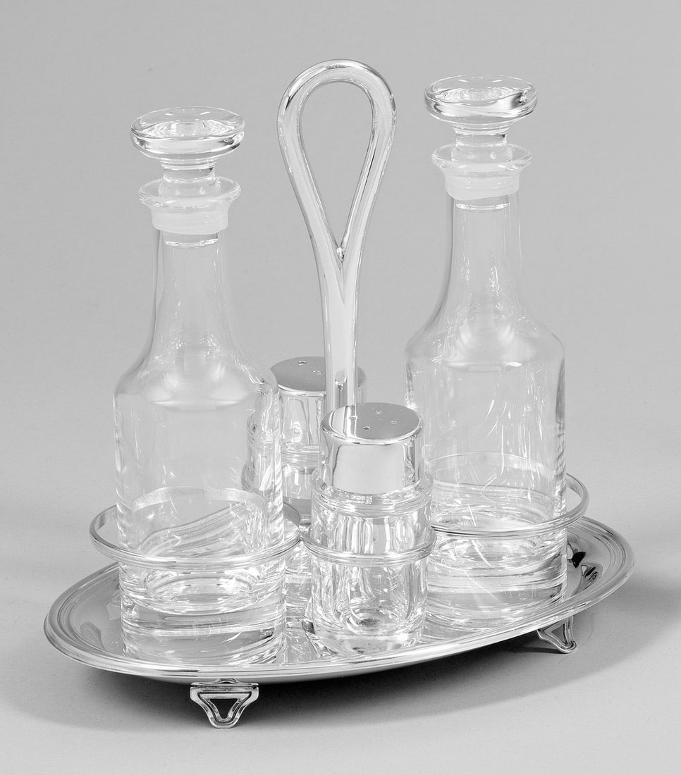 Menage: Silber. 5-tlg.; Ovaler Stand mit profiliertem Rand, mittig aufsteigender, ovaler Griff. Unterhalb vier Halteringe für Essig- und Ölflasche sowie Pfeffer- und Salzstreuer aus farblosem Glas, teilw. m