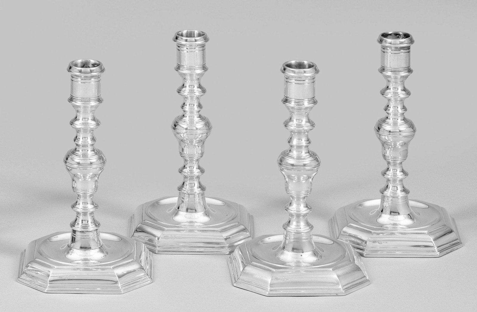 Satz von vier Tafelleuchtern: Silber, beschwert. Eckiger, mittig gemuldeter Stand. Balusterschaft mit mehreren gedrückten, profilierten Nodi und zylindrische Tülle. Gest. 800, Beschauzeichen, Herstellerzeichen. Ges.-Gew. ca. 170