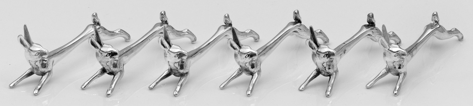 Sechs figürliche Messerbänke: Sterlingsilber. Vollplastisch gearbeitet in Gestalt von Hasen. Gest. 925. Gew. zus. ca. 275 g. L. 8,5 cm. Six Sterling Silver knife rests in form of rabbits. Standard mark 925. Deutsch. 20. Jh.