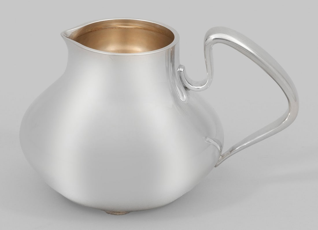 Georg Jensen-Sahnegießer: Sterlingsilber. Gedrückt birnförmiger Korpus mit angedeutetem Konsolausguss und rückseitigem, geschwungenem Bandhenkel. Gest. 925 sowie "Denmark Sterling", Entwerfer-Monogramm "HK" für Entw. Henni