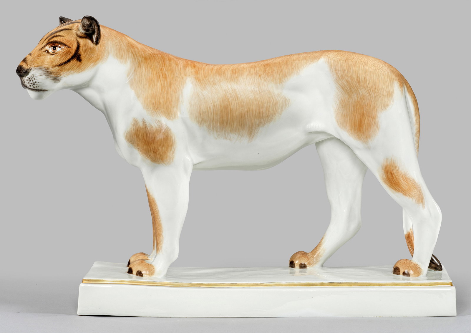 Große Meissen Tierfigur einer Löwin: Auf rechteckig profiliertem Sockel stehende, aufmerksam beobachtende Löwin mit naturalistischer Fellzeichnung. Polychrome Malerei mit dezenter Goldkonturierung. Entw. August Gaul. Entw.-Bez.; Modell-