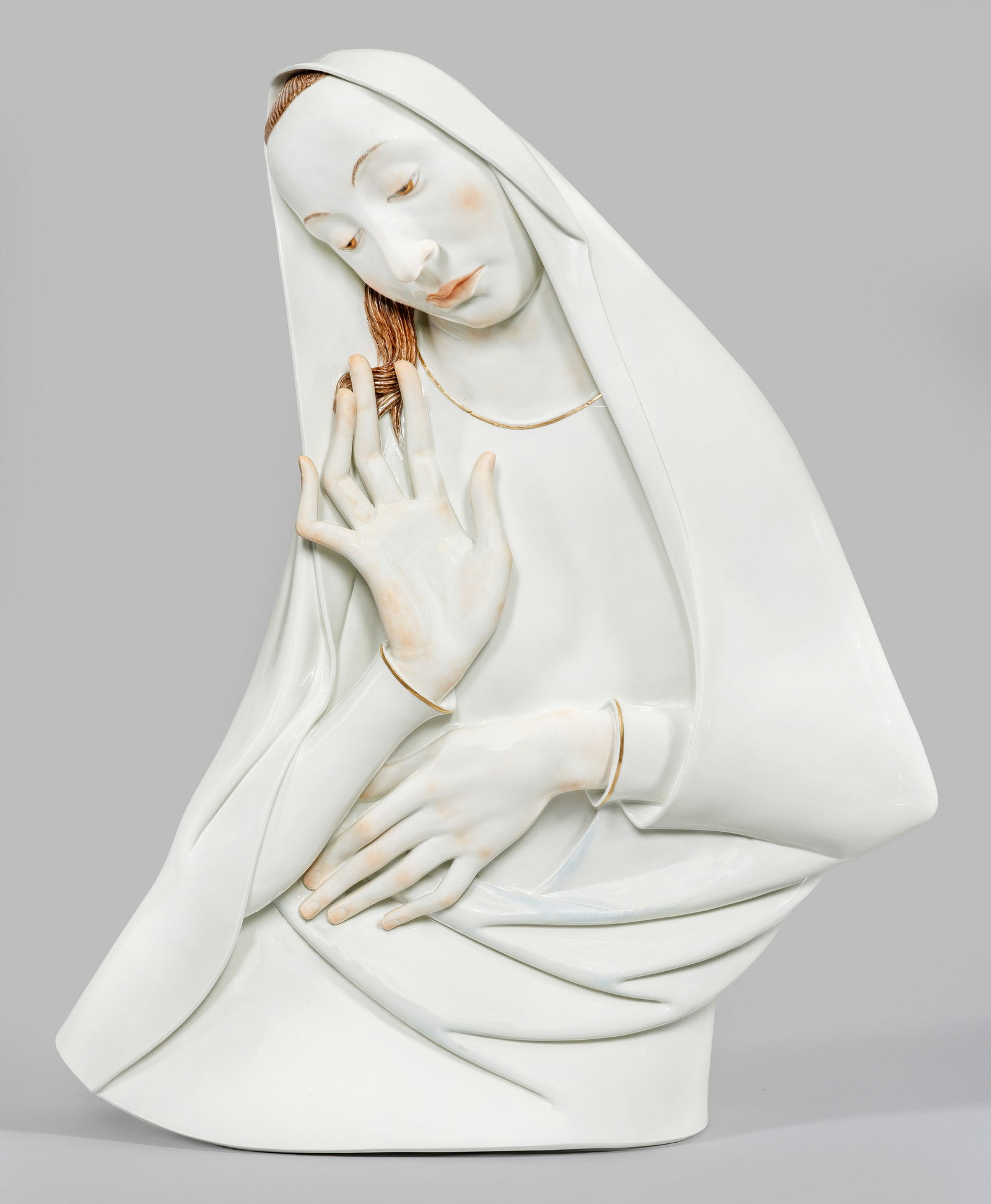 Große Art Déco-Madonna von Meissen: Halbfigurige Darstellung der in sich gekehrten, sehr schlanken, jungen Maria. Bogenförmig geschwungener, in ein schlichtes Tuch gehüllter Körper mit expressiv angewinkelten Armen und Händen. Feine