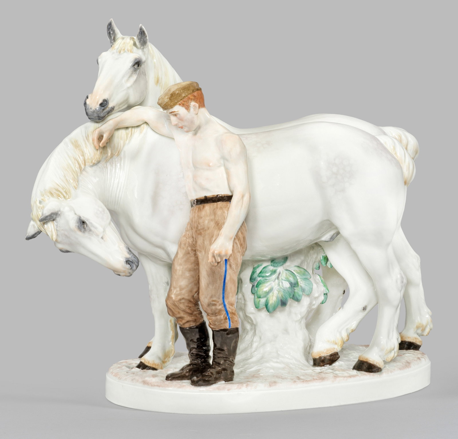 Seltene Meissen Figurengruppe "Kamerad-Pferd": von Erich Oehme Auf naturalistischer Ovalplinthe stehender oberkörperfreier Soldat, die zwei Araber-Schimmel umsorgend. Feine polychrome Malerei. Entw. Erich Oehme, um 1942 - 1943. Entw.-Bez. mit Dat