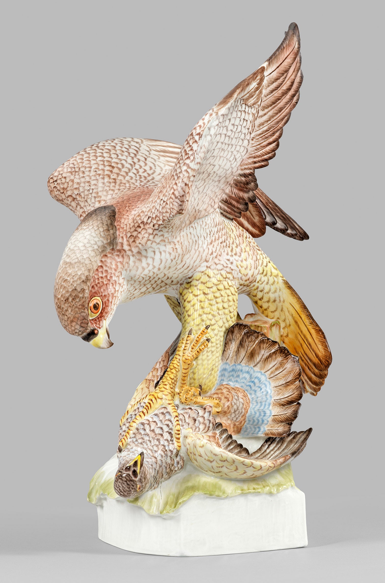 Großer Meissen Jagdfalke mit Beute von Max Esser: Auf begrüntem Steinsockel die naturalistische Darstellung eines majestätischen Falken, der einen kleinen Raubvogel zu seiner Beute macht. Fein gestrichelte Fellzeichnung. Feine polychrome Malerei. E