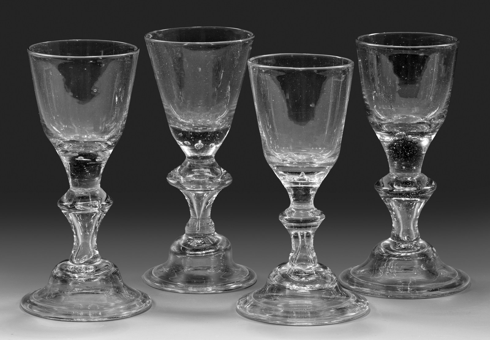 Vier Lauensteiner Barock-Pokale: Farbloses Glas. Glockenfuß, umgeschlagener Rand, im Balusterschaft eine große, eingestochene Luftblase, im Ansatz der konischen Kuppa sieben oder neun kleine Luftblasen. H. 15,7 cm-16,3 cm. Four Nor