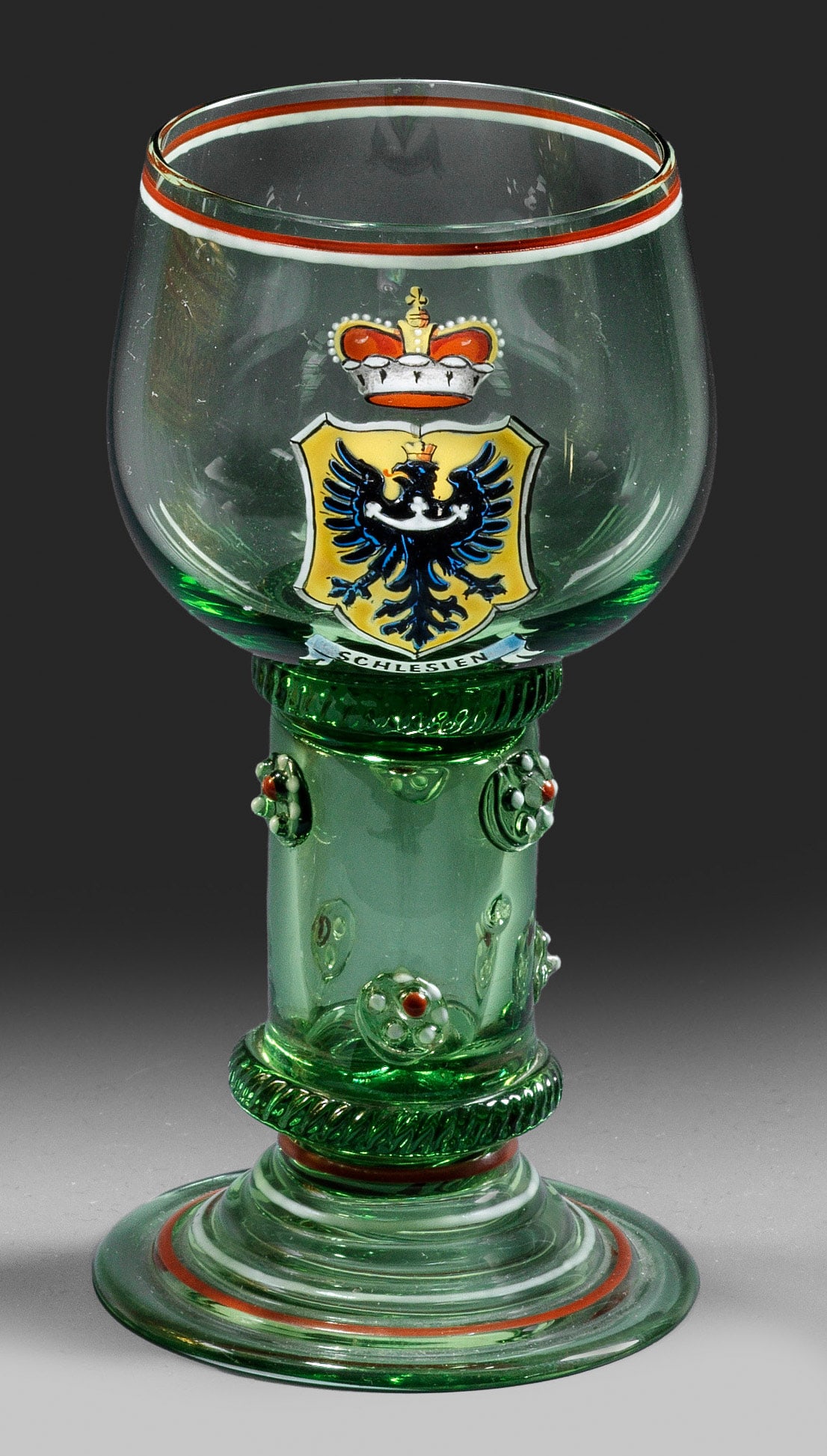 Lobmeyr-Römer mit Wappen von Schlesien: Grünes, transparentes Glas. Profilierter Glockenfuß, hohler Schaft mit Beerennuppen und zwei gekniffenen Fadenauflagen zum Fuß und zur Kuppa. Auf der Kuppa das Wappen von Schlesien mit Fürstenhut 