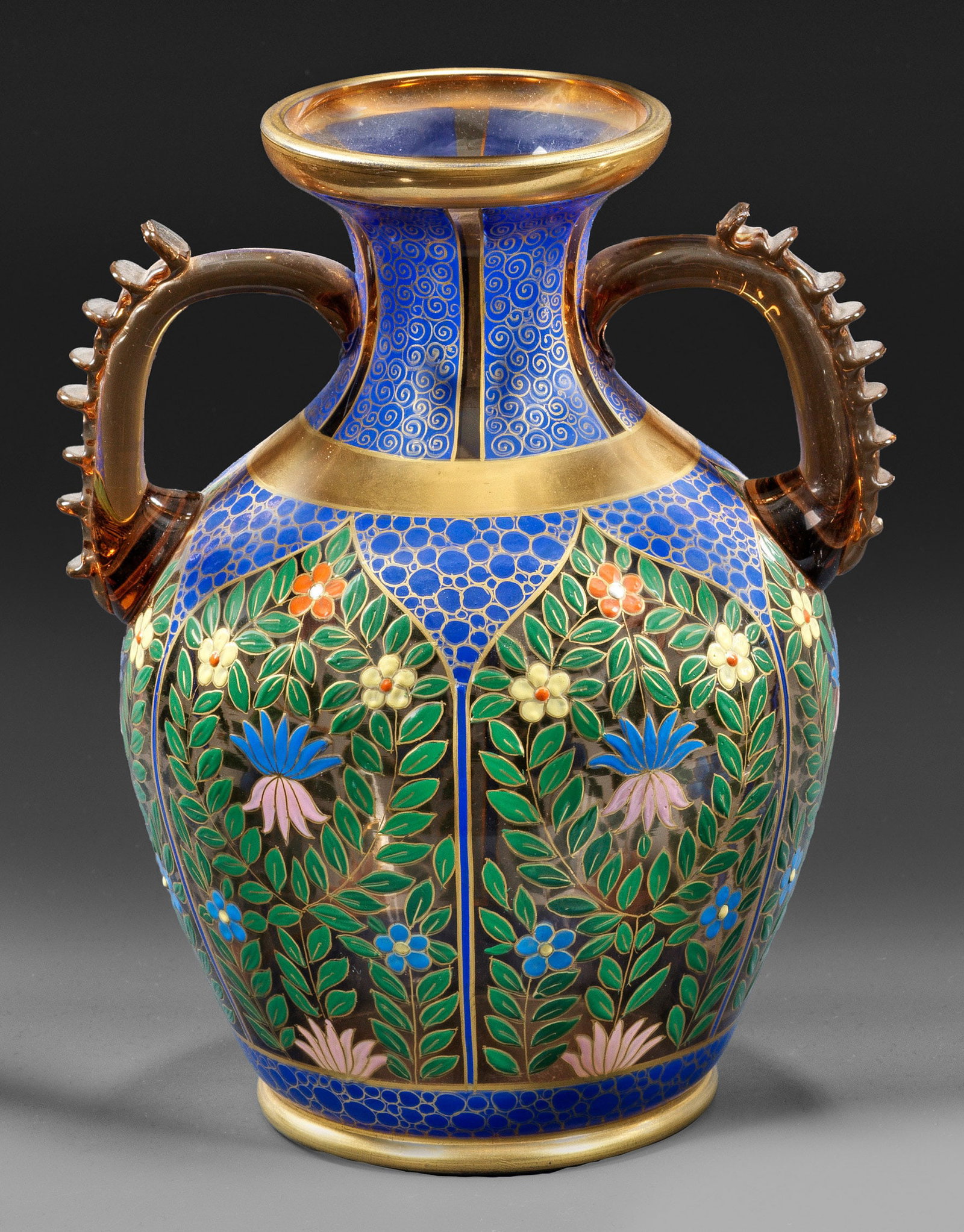 Doppelhenkelvase mit orientalisierendem Dekor: aus der "Serie im Persischen Style" Rauchfarbenes, transparentes Glas. Balusterform, auf den Ohrenhenkeln gekniffene Fadenauflagen. Reicher, flächendeckender, ornamentaler Dekor in polychromer, opake