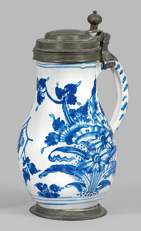 Birnenkrug mit Blumendekor: Fayence. Bauchig gewölbter Korpus in zylindrischen Hals übergehend. Zinnmontierter Ohrhenkel- und Deckel mit Kugeldrücker. Umlaufend der Wandung sommerliche Blumenstauden. Kobaltblauer Scharffeuerd
