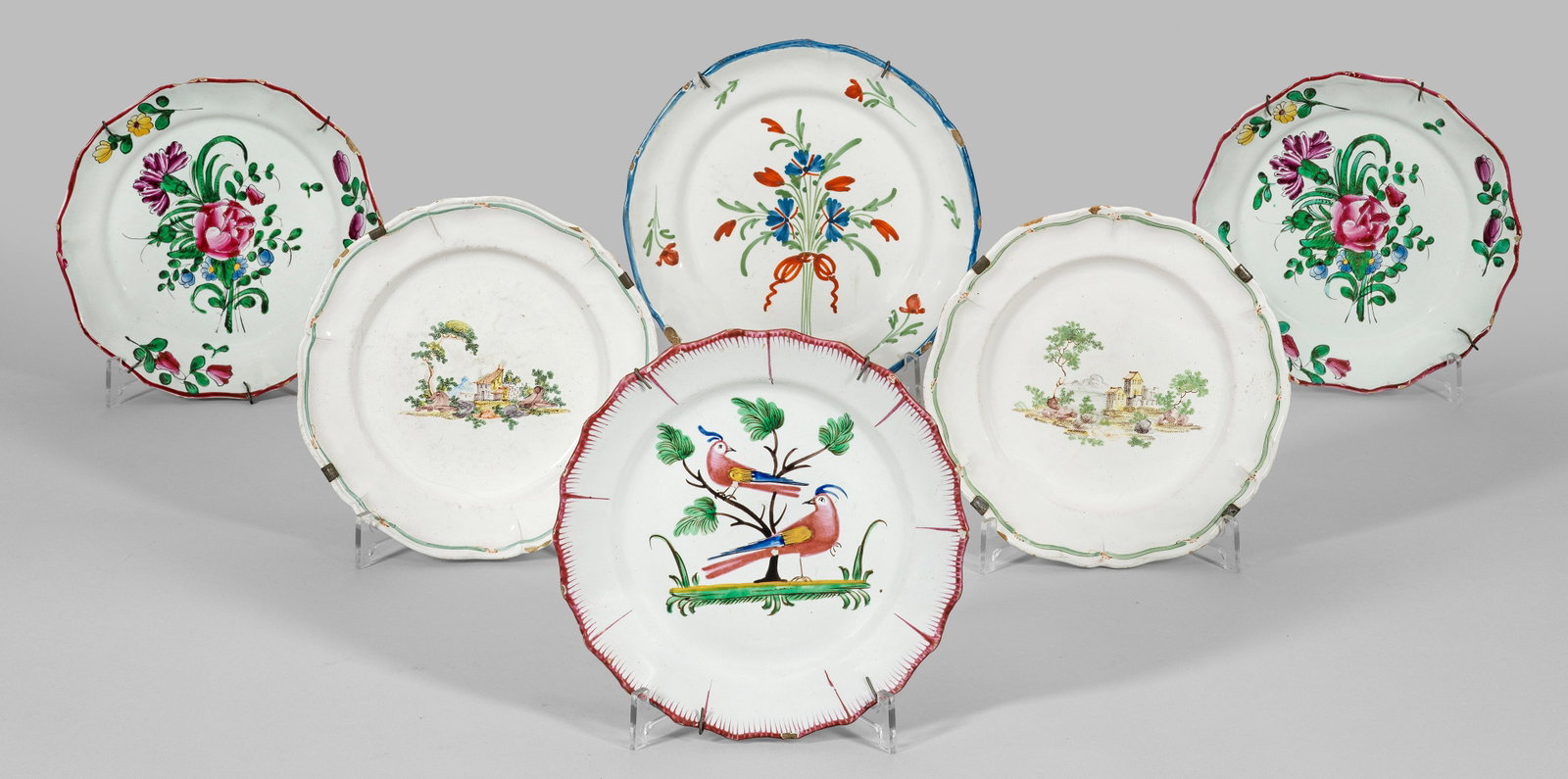 Sechs Teller mit Blumen- und Landschaftsdekor: Fayence. Runde Form mit passig geschweiftem Rand. Im vertieften Spiegel und auf der Fahne Blumengebinde, Landschaftsinseln mit Dorfidyll sowie zwei Papageien auf Ast. Polychrome Malerei. Best.; D. 21 