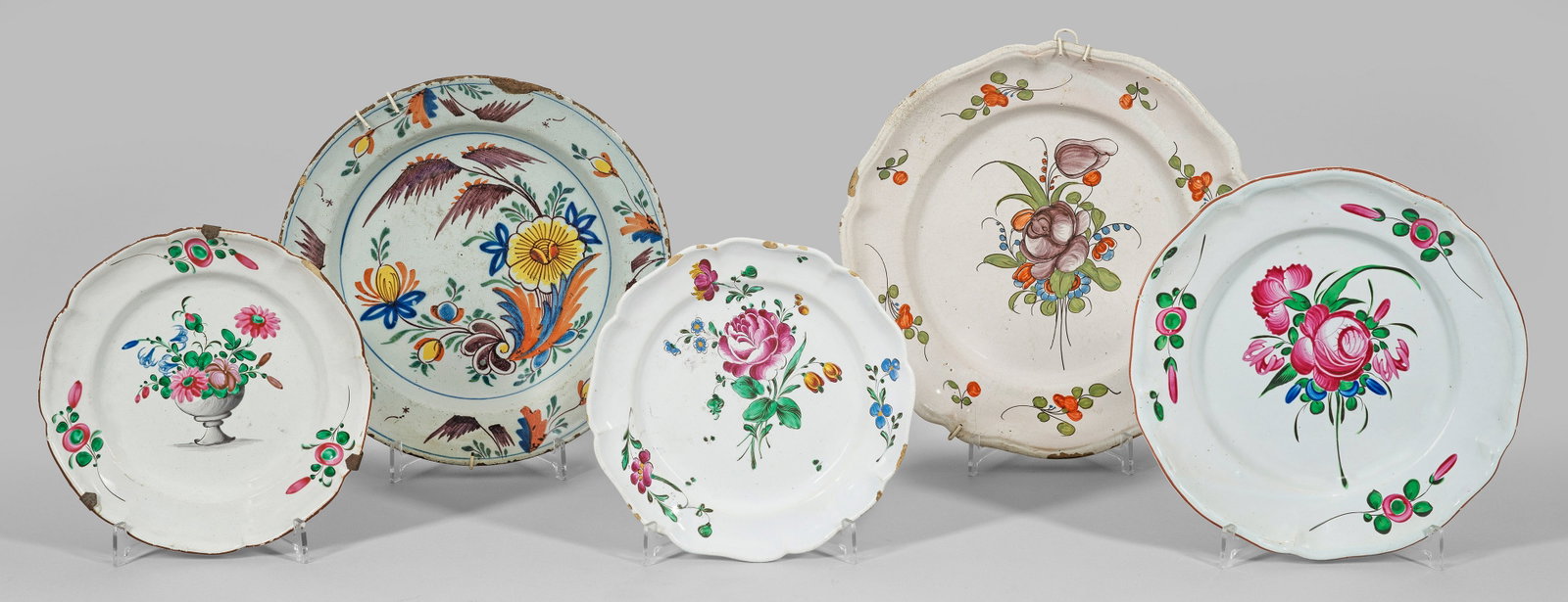 Fünf Teller mit Blumendekor: Fayence. Runde, zumeist passig geschweifte Form. Im Spiegel und auf der Fahne Blumendekore in polychromer Malerei. Partiell best.; D. 23,5 cm - 33 cm. Provenienz: Auflösung der Privatsammlung Horst S