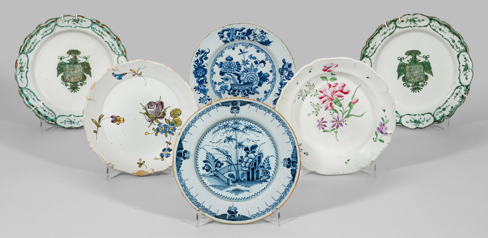Sechs Teller mit Wappen- und Blumendekor: Runde, zumeist passig geschweifte Form. Im Spiegel von einem Adler gehaltenes Wappen der spanisch-habsburgischen Monarchie, bunte Blumendekore, blaue, asiatische Gartenlandschaft bzw. Päoniendekor im