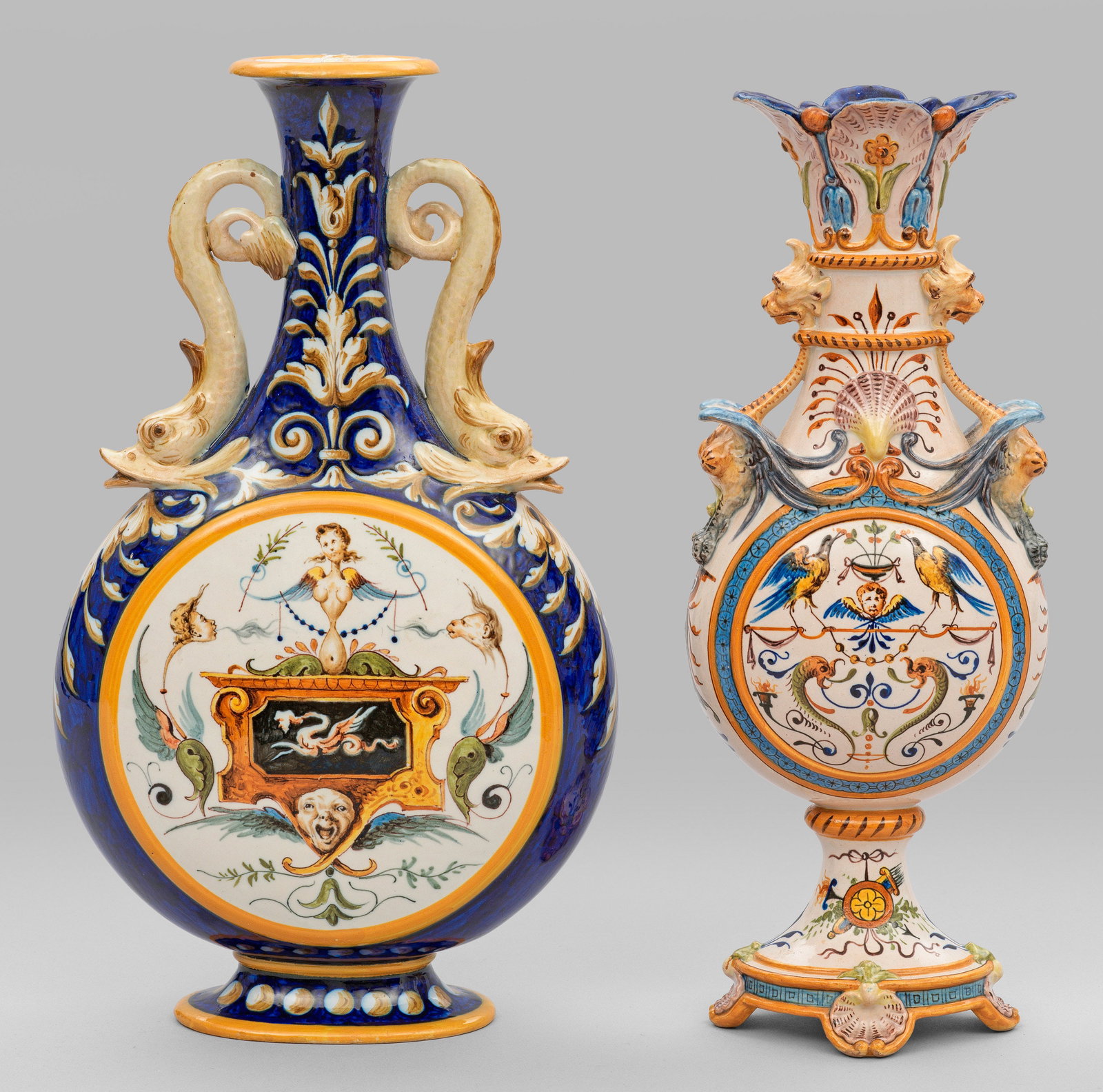 Zwei Historismus-Vasen im Renaissance-Stil von Ginori: Majolika. Beidseitig abgeplattete Pilgerflaschenform mit Enghals und plastischen Delphinhenkeln bzw. gefußte, ins Oval gedrückte Flaschenform mit reliefplastischen Grotesken. Reicher Dekor und Staff