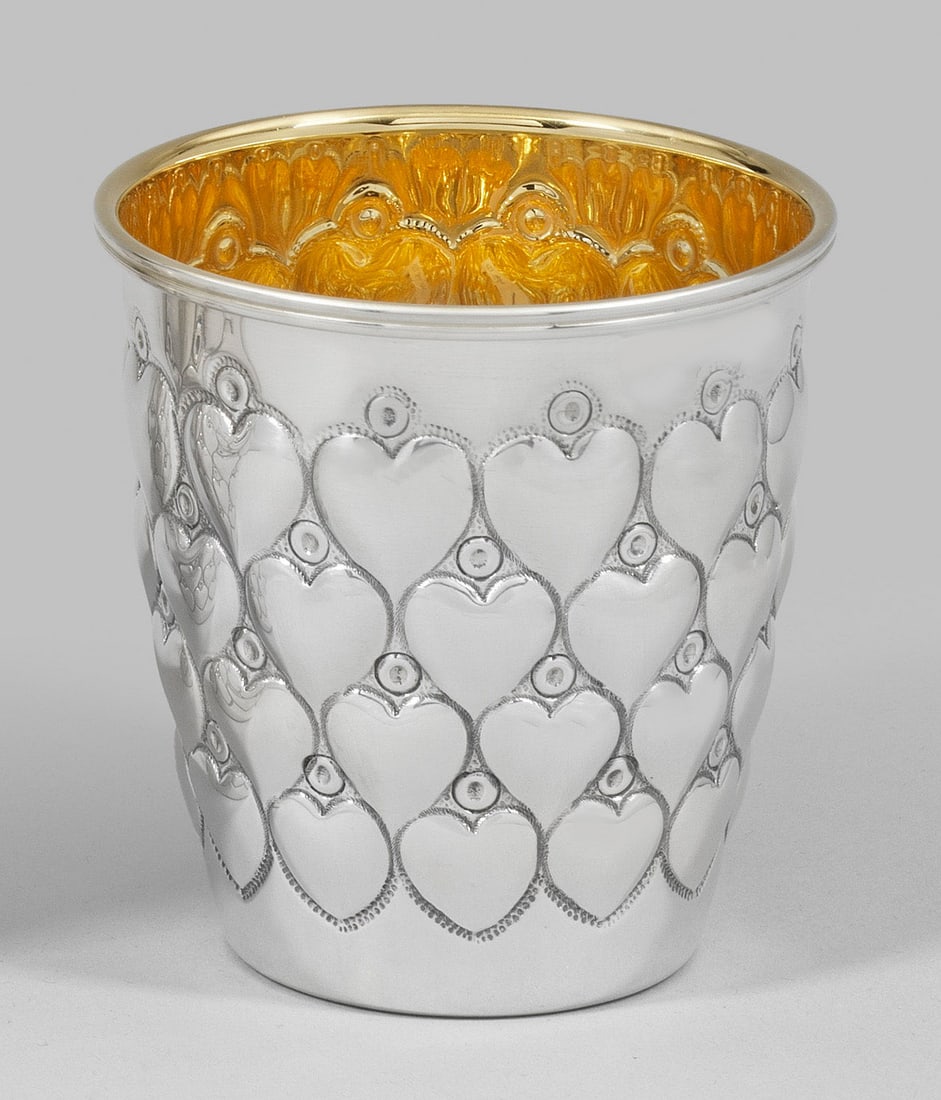 Herzbecher: Sterlingsilber. Gering konisch mit glattem Lippenrand. Wandung vierreihig versetzt umzogen von reliefplastischen Herzen. Innen vergoldet. Gest. 925. Gew. ca. 105 g. H. 8 cm. A German Sterling silver b