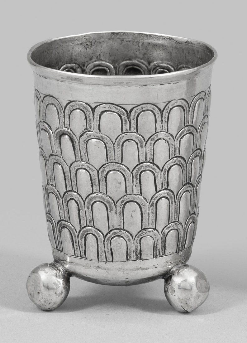 Kugelfußbecher mit Schuppendekor: Silber. Konischer, von drei ausgestellten Kugelfüßen getragener Korpus mit umlaufendem gravierten, punzierten Schuppendekor und profiliertem Rand. Best./rest.; Gest. Beschauzeichen, ungedeutetes Mei