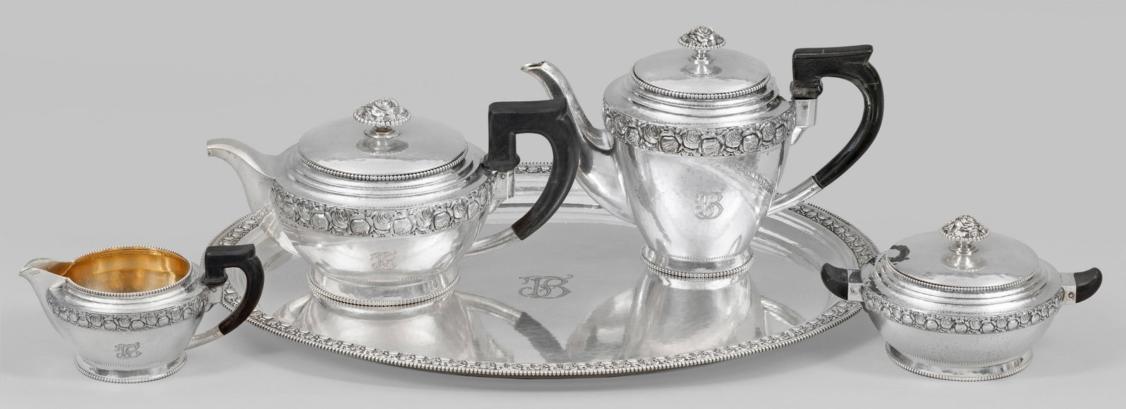 Kaffee- und Teeservice mit Rosendekor: Silber. 5-tlg.; Kaffeekanne, Teekanne, Zuckerschale, Sahnegießer, Tablett. Rundfuß mit Perlstab gesäumt, gedrückt bauchiger Korpus mit die Schulter umlaufendem Rosenrelief und schauseitiger Monogr
