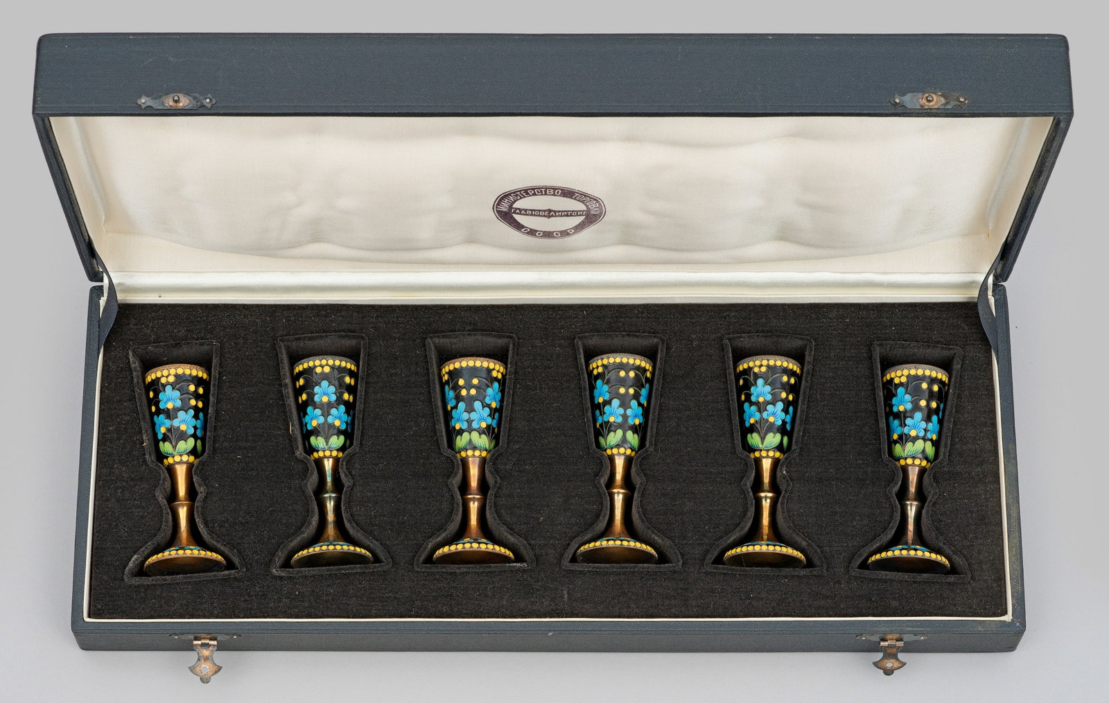 Sechs Cloisonné-Wodkabecher: Silber, vergoldet, teilw. emailliert. Runde Form mit leicht aufgewölbtem Fuß, hohem Balusterschaft und konischer Kuppa. Fuß und Kuppa ornamentiert mit polychromem, schwarzgrundigem Zellenschmelzema