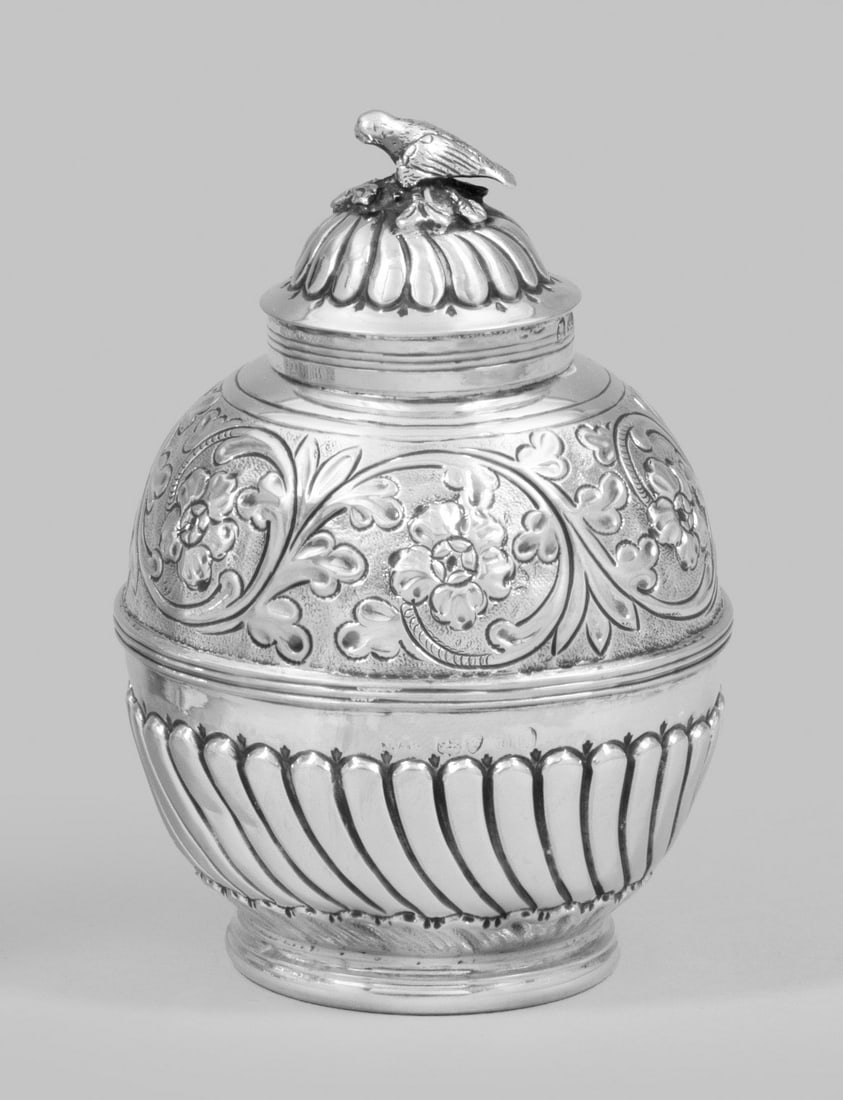 Georg VI-Deckeldose: Sterlingsilber. Auf rundem Standring kugelförmiger Korpus mit gedrehtem Zungendekor in der unteren Wandungshälfte und blütenbesetzten Voluten in der oberen. Zylindrischer Hals mit aufgewölbtem Ste