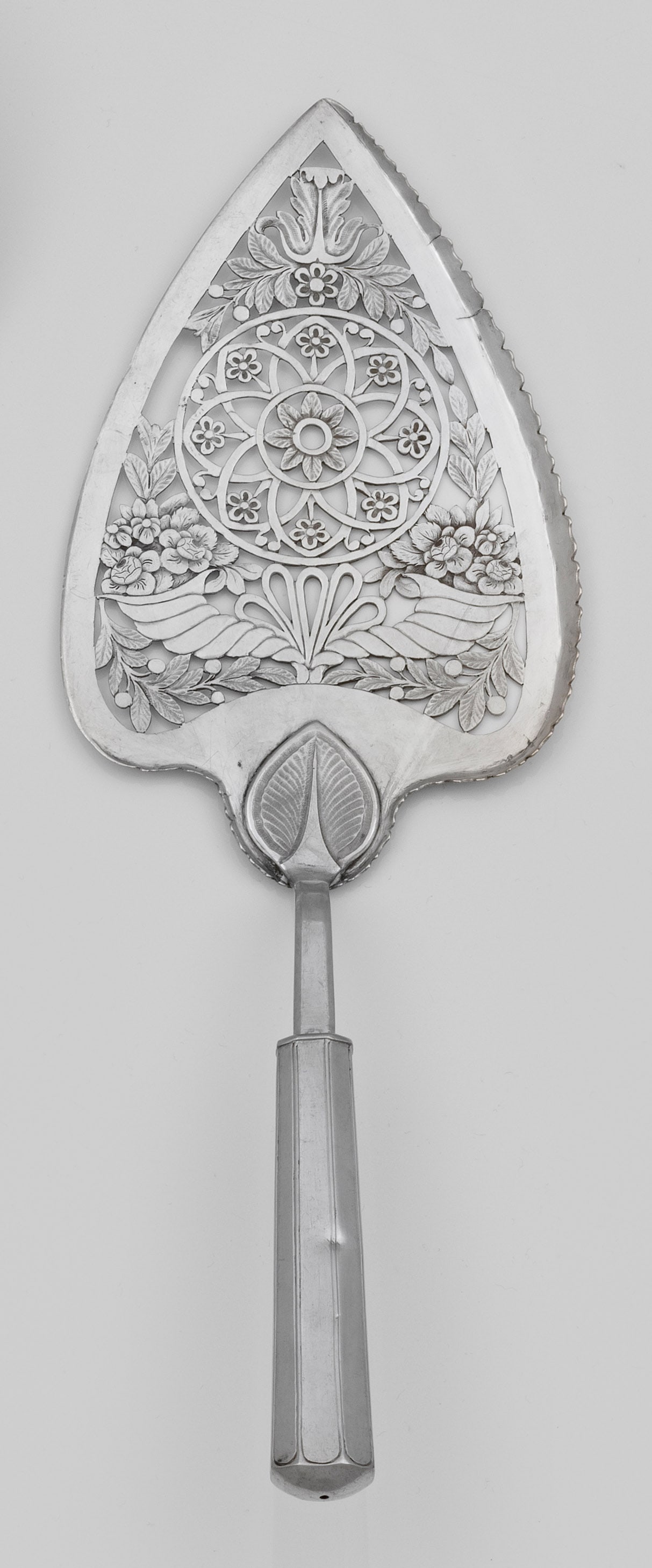 Biedermeier-Pastetenheber: Silber. Längliche, herzförmige, durchbrochen gearbeitete Laffe mit Blüten, Blättern und zwei Füllhörnern sowie Ansatz in Form eines Blattes. Der Griff konisch und achtfach gekantet. Risse, klein