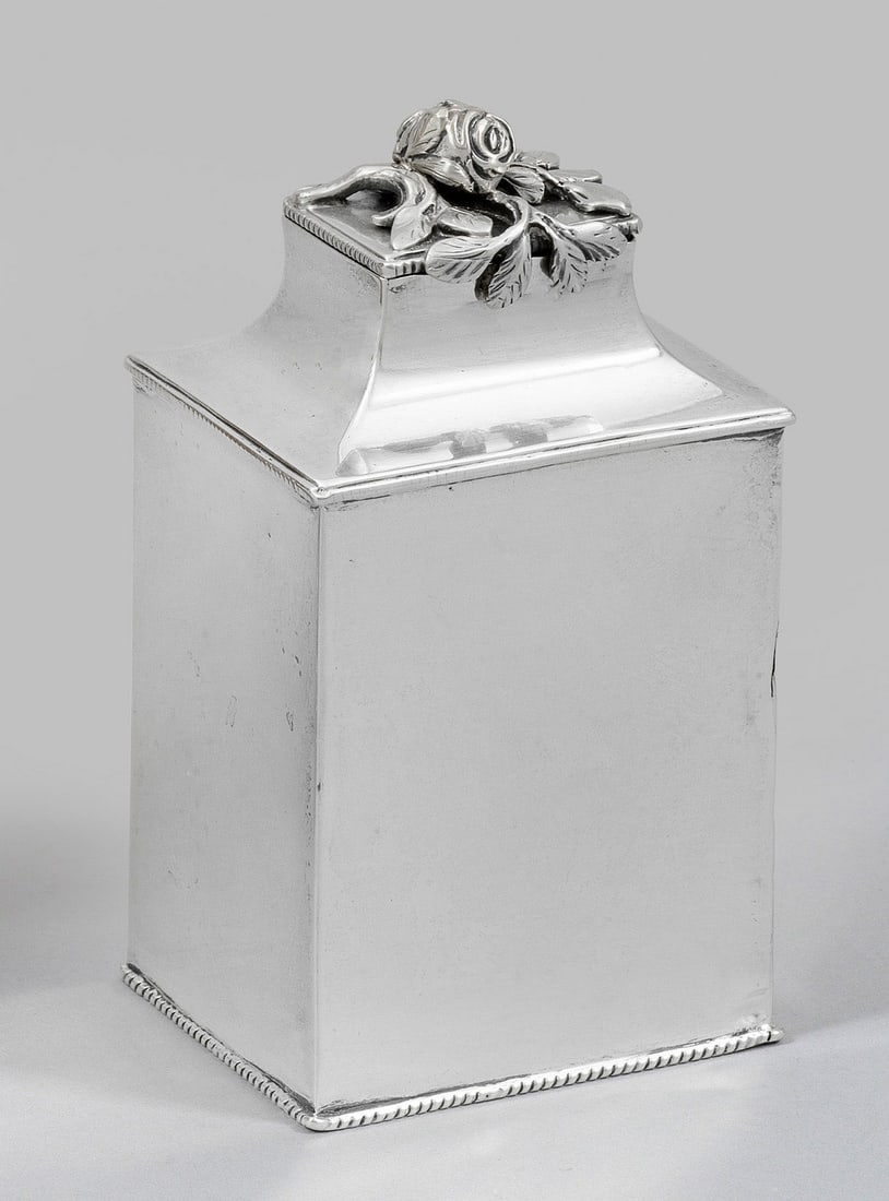 Georg III-Teedose: Sterlingsilber. Hochrechteckiger Korpus mit eingezogenem Hals, Stopfdeckel mit plastischem Blumendekor belegt. Stand, Schulter und Deckelrand umzogen mit Kordelband- bzw. Perlstabdekor. Gerissen. Gest