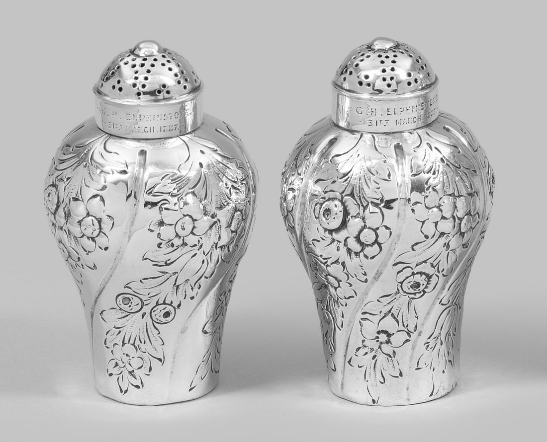 Paar Georg III-Streuer: Sterlingsilber. Auf runder Standfläche balusterförmiger Korpus und aufgewölbter, durchbrochen gearbeiteter Deckel. Wandung mit geschwungenen, senkrechten Zügen, Blättern und Blüten ornamentiert.