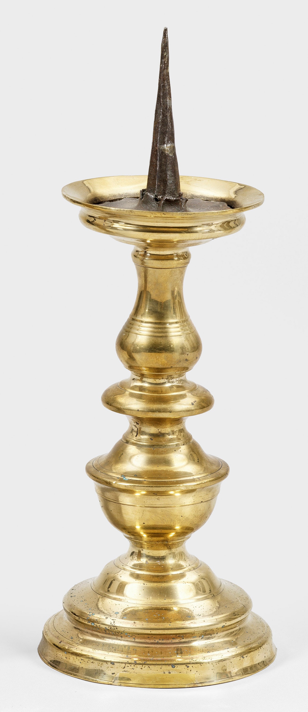 Großer Renaissance-Dornleuchter: Messing. Trompetenförmiger, aufgewölbter Stand, übergehend in mehrfach durch Kehlungen und Wülste gegliederten Schaft. Tropfschale mit hochgezogenem Rand und zentralem, hohem Dorn. H. 38 cm. Vgl. 