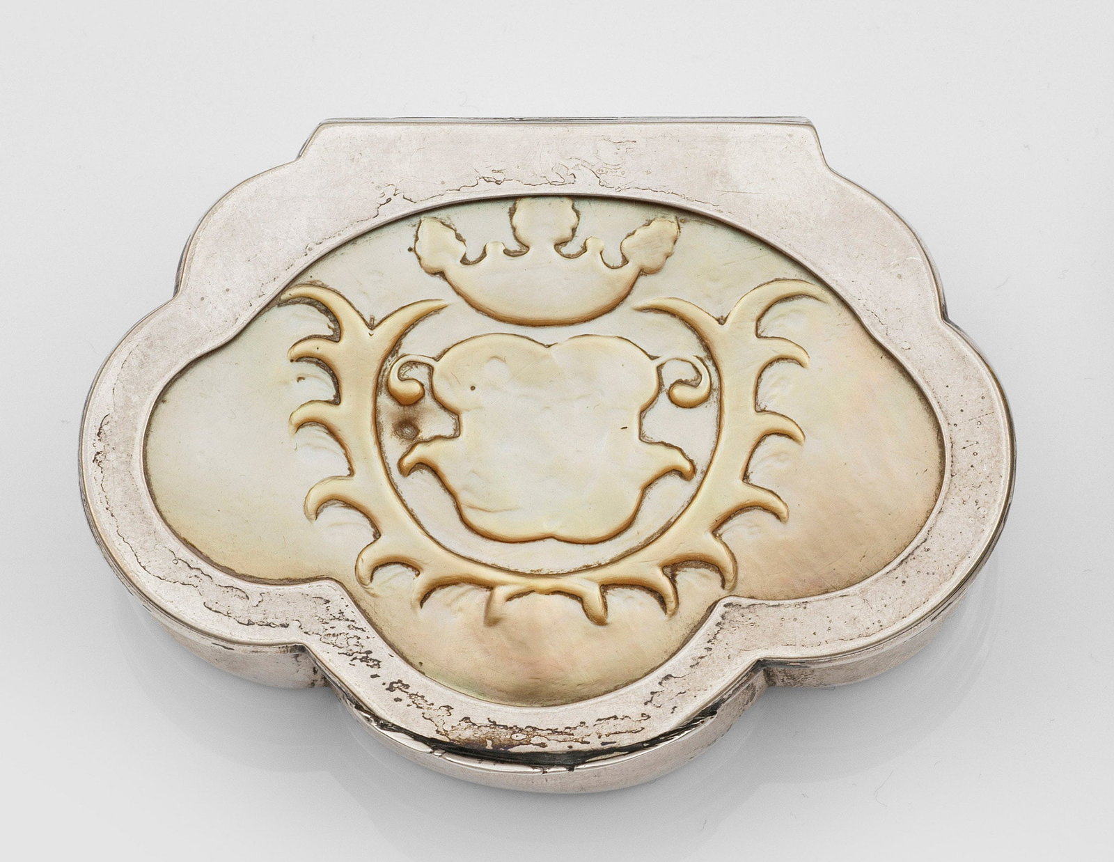 Barock-Tabatiere: Silber, Perlmutt. Muschelförmige Grundform, flacher Stand und leicht gebauchte, mehrfach durch vertikale Züge gegliederte Wandung. Im flachen, rückseitig scharnierten Deckel eingesetzte Perlmuttpla
