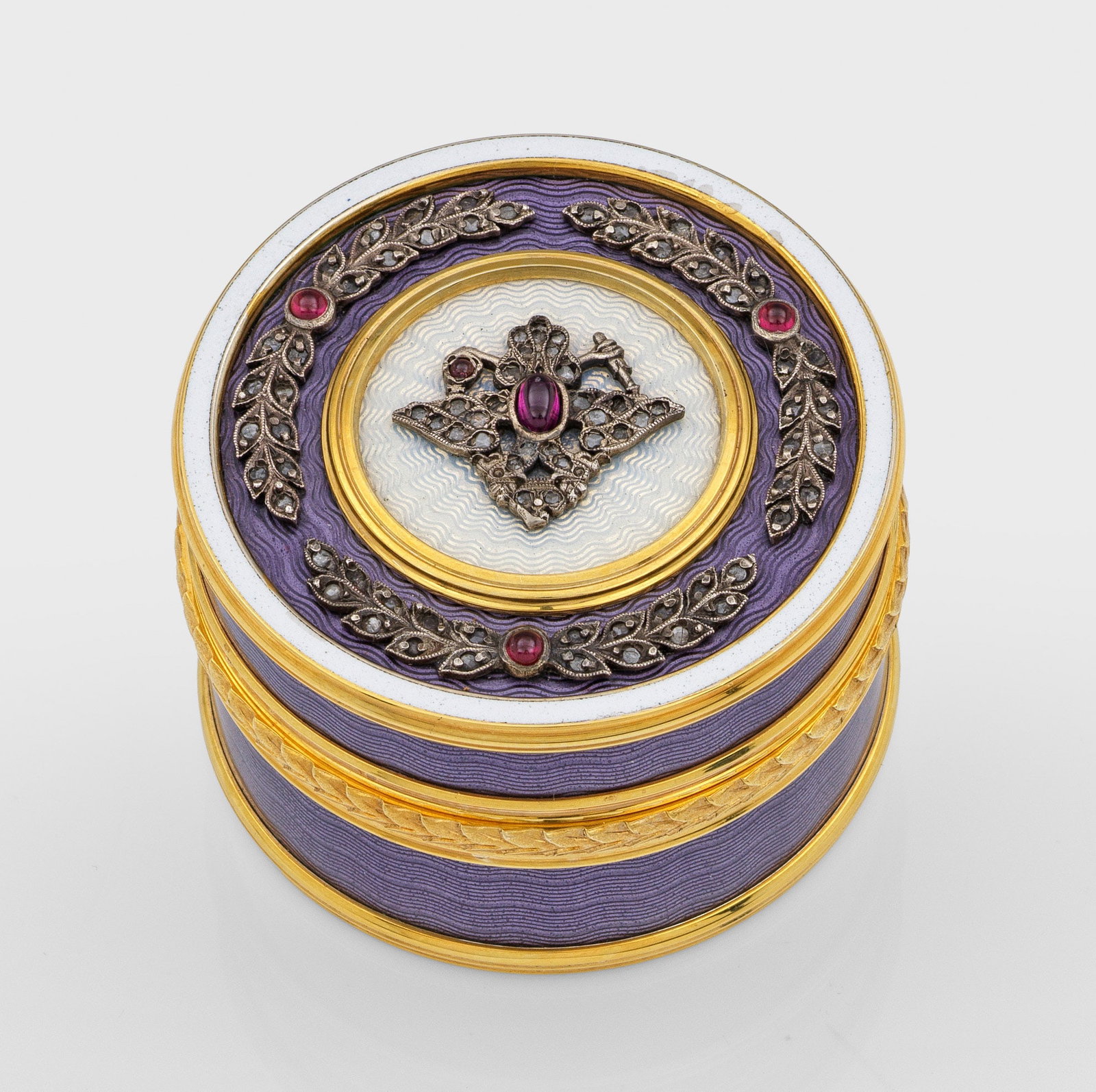 Zierdose mit Doppeladler: im Stil von Karl Fabergé. Silber, teilw. vergoldet und emailliert. Runde, zylindrische Form. Der flache Stülpdeckel wellenförmig guillochiert und weiß und fliederfarben emailliert. Darauf zwischen