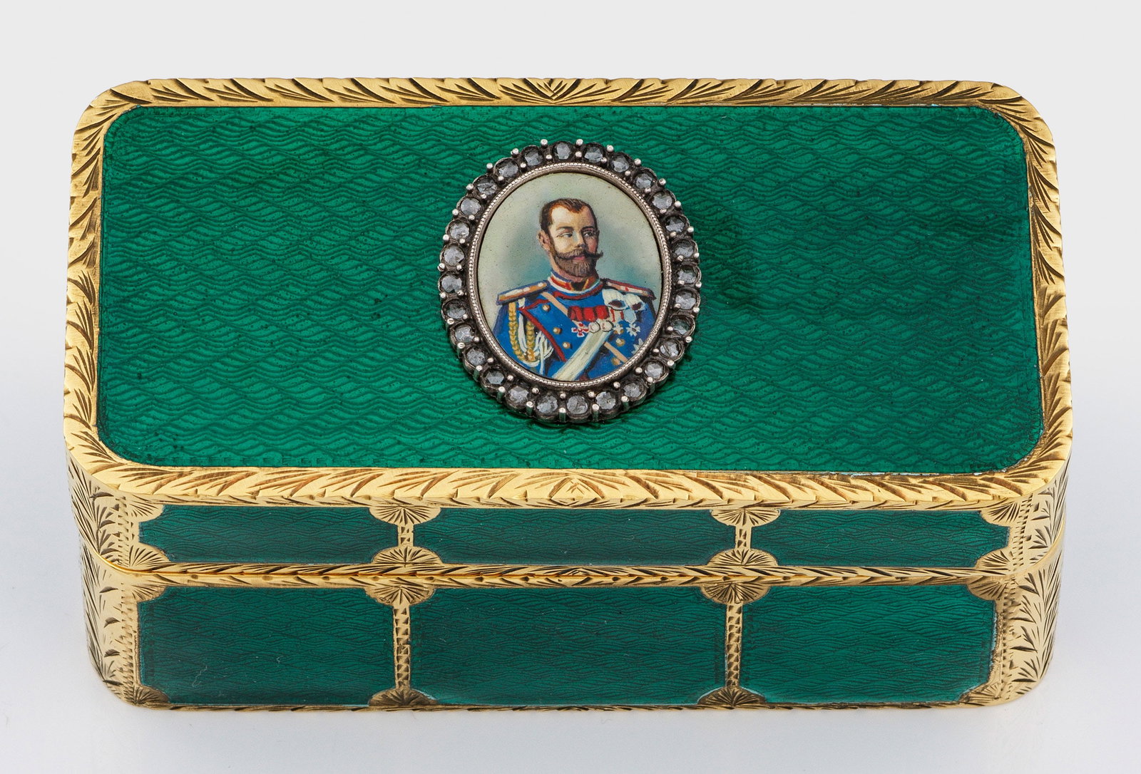 Repräsentative Email-Zierdose: im Stil von Karl Fabergé. Silber, vergoldet und teilw. emailliert. Rechteckig, mit gerundeten Ecken. Die Wandung und der scharnierte Deckel zwischen vergoldeten Ornamentbändern und -rändern wellenf