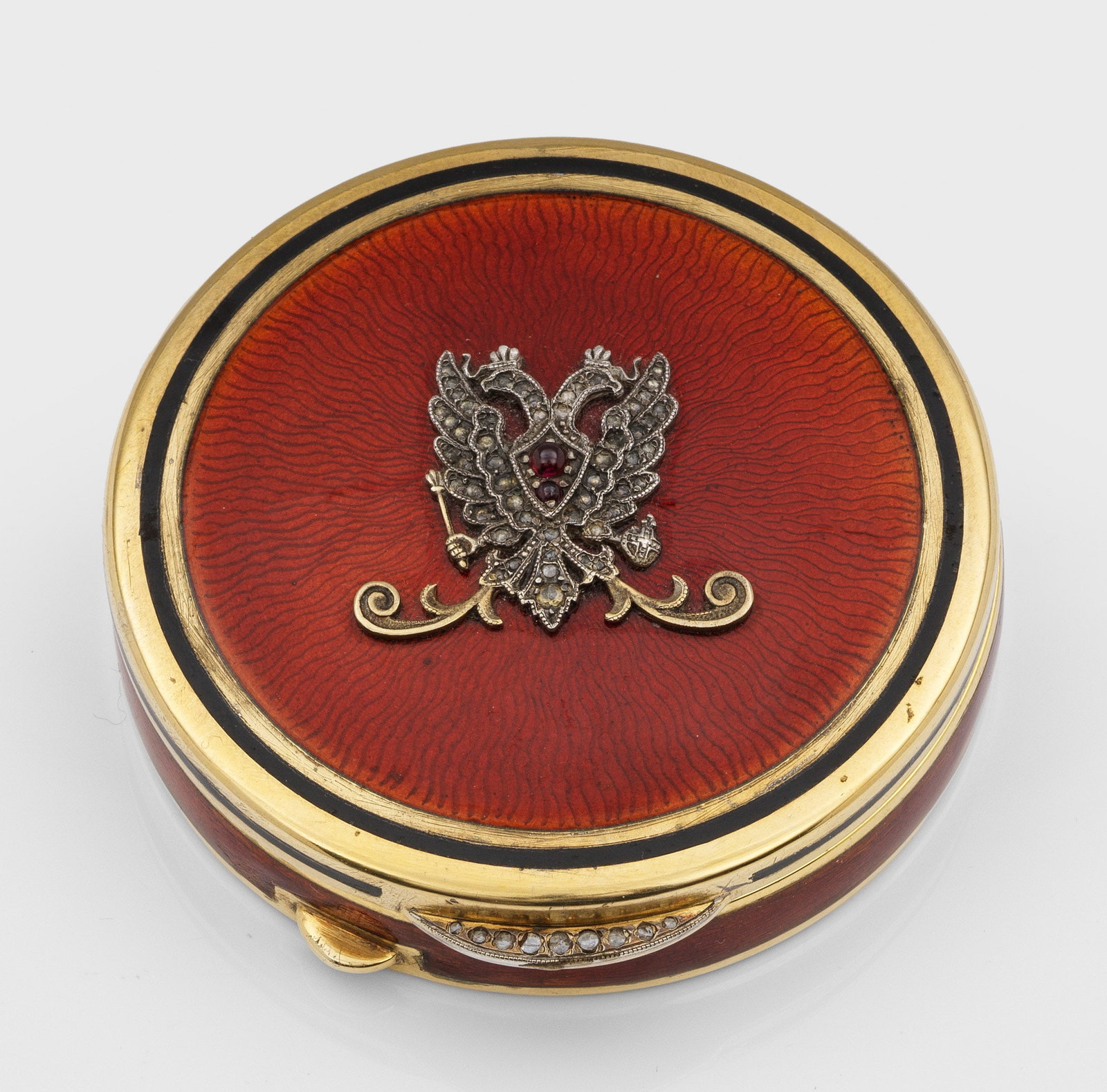 Dekorative Emaille-Dose: im Stil von Karl Fabergé. Silber, vergoldet und teilw. emailliert. Runder Korpus. Auf dem gering aufgewölbtem Scharnierdeckel applizierter Doppeladler, ausgefasst mit kleinen Diamantrosen und